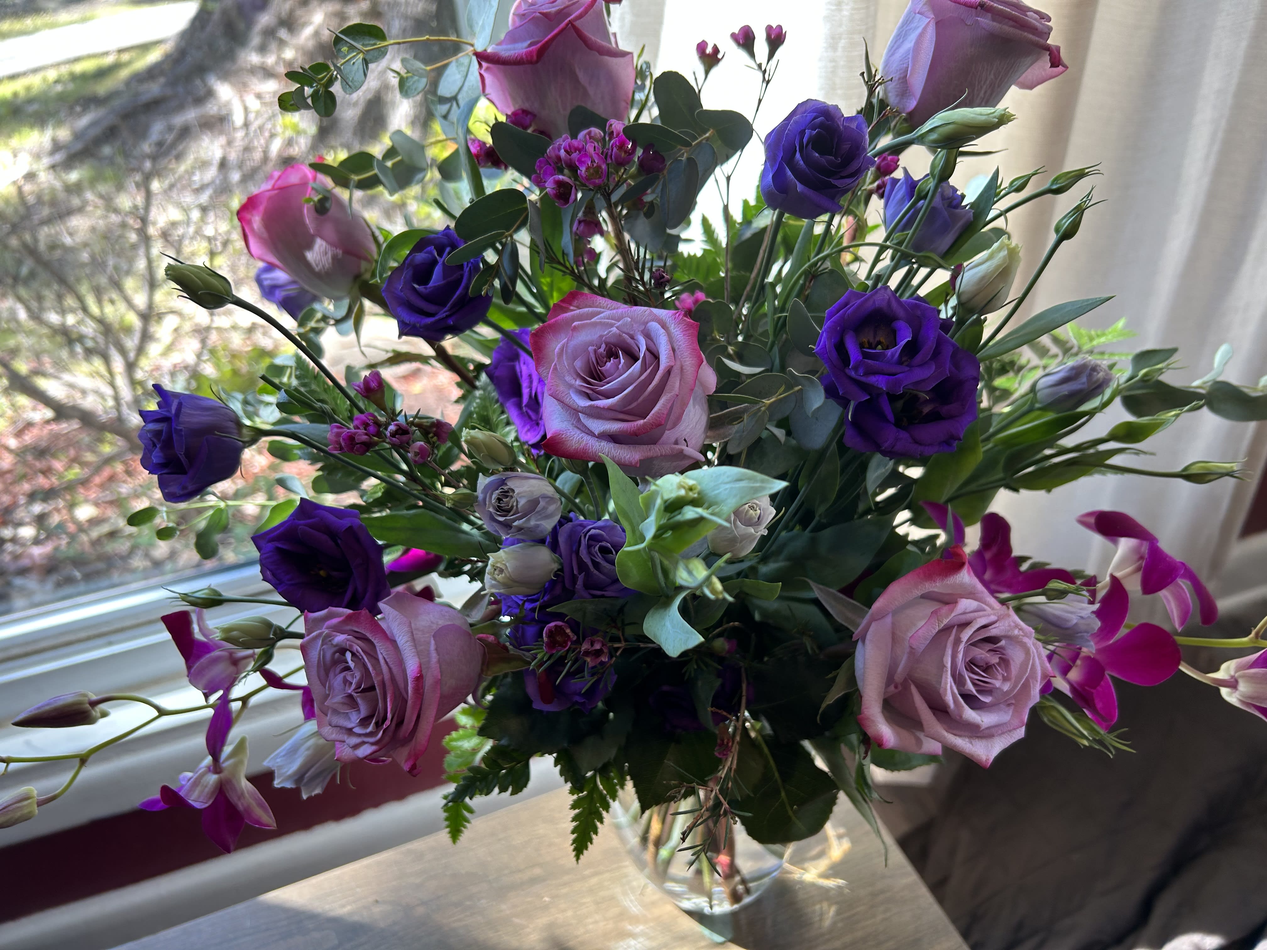 Bouquet of pink and purple roses in a clear glass vase