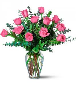 Pink roses arranged in a clear glass vase with greenery
