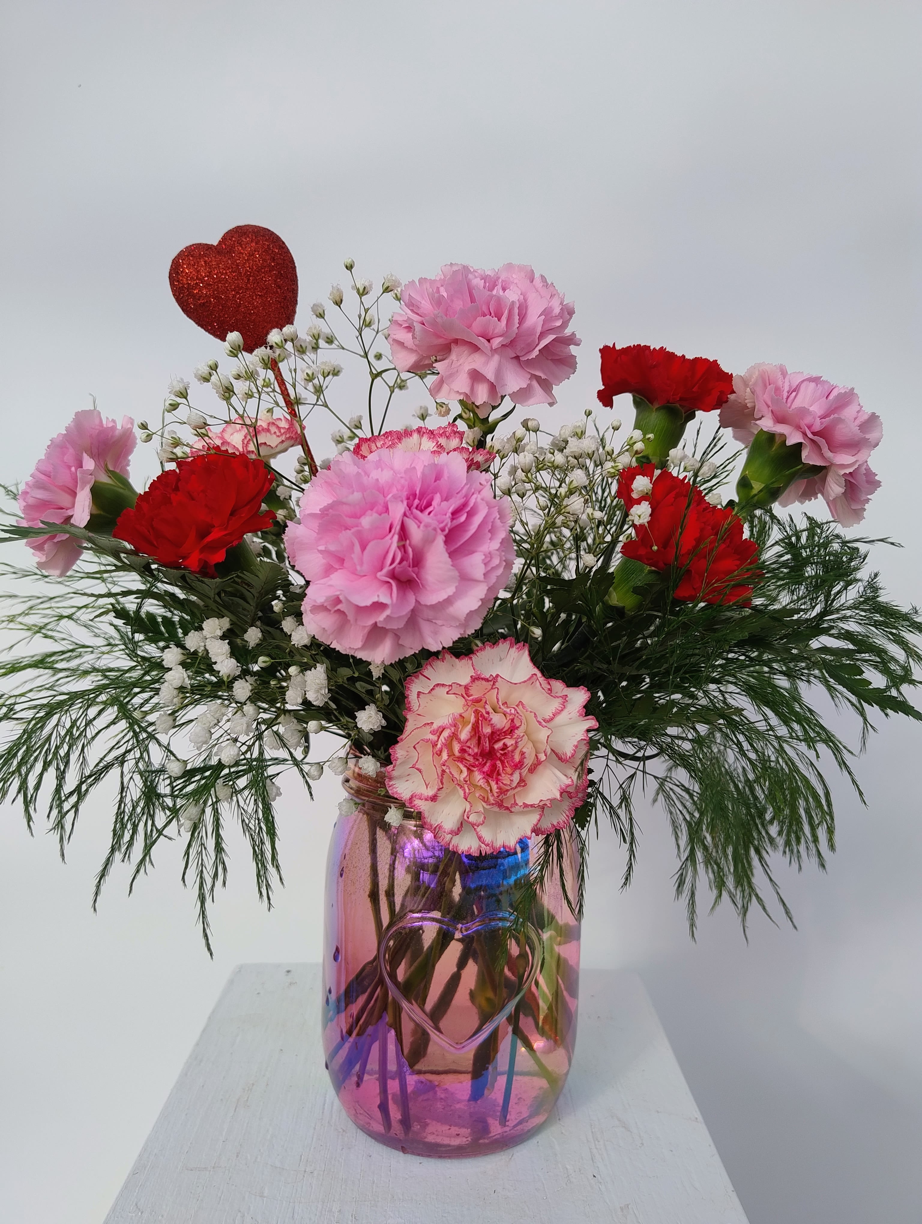Love You - This keepsake iridescent pink mason jar with an embossed heart is filled with Valentine's Day-colored carnations and baby's breath for all those old school carnation lovers. Comes with glittery red heart pick. Perfect to show your love to all the valentines in your life!