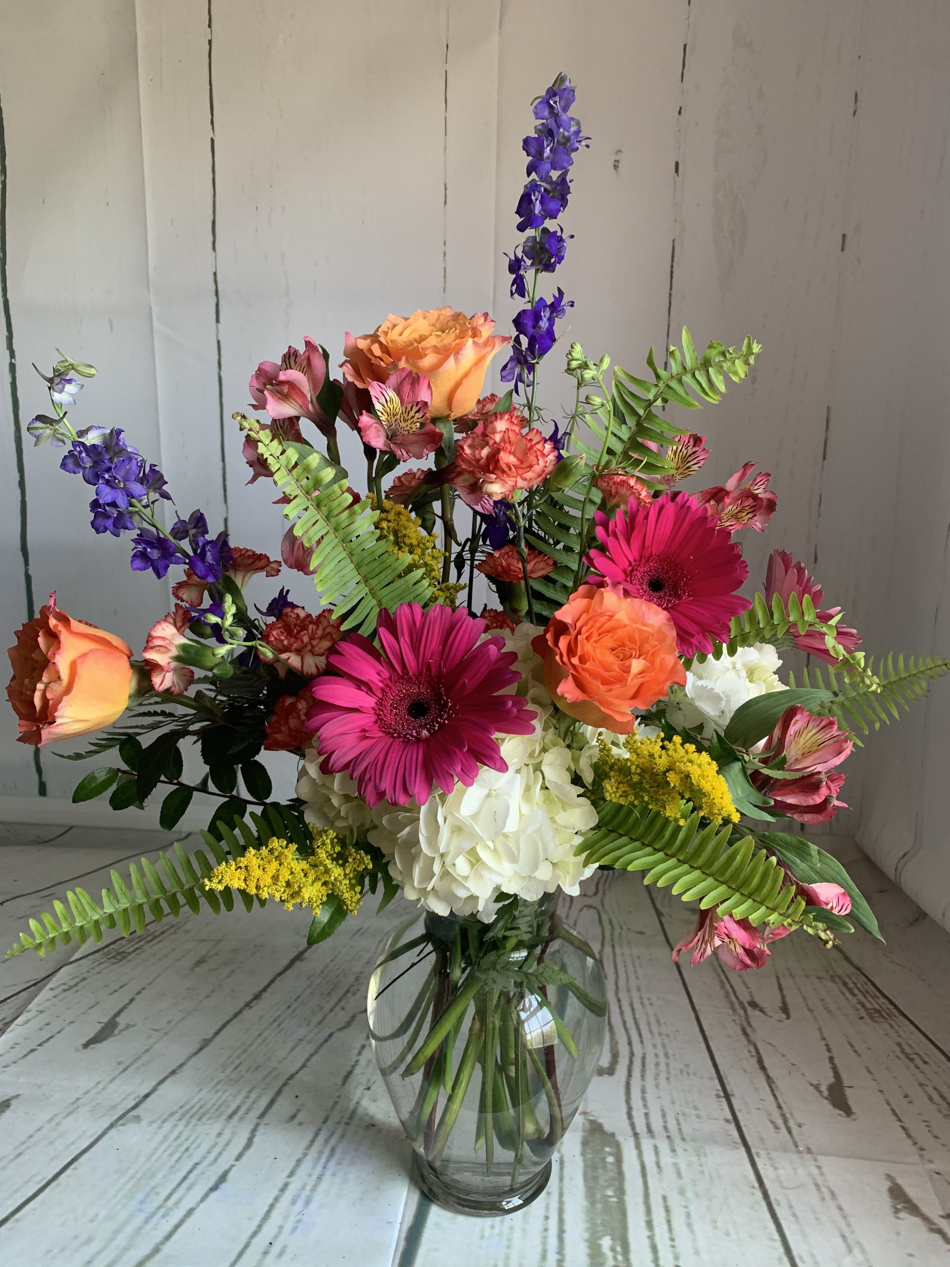 Mixed bouquet in a glass vase with pink gerberas, orange roses, and white hydrangea