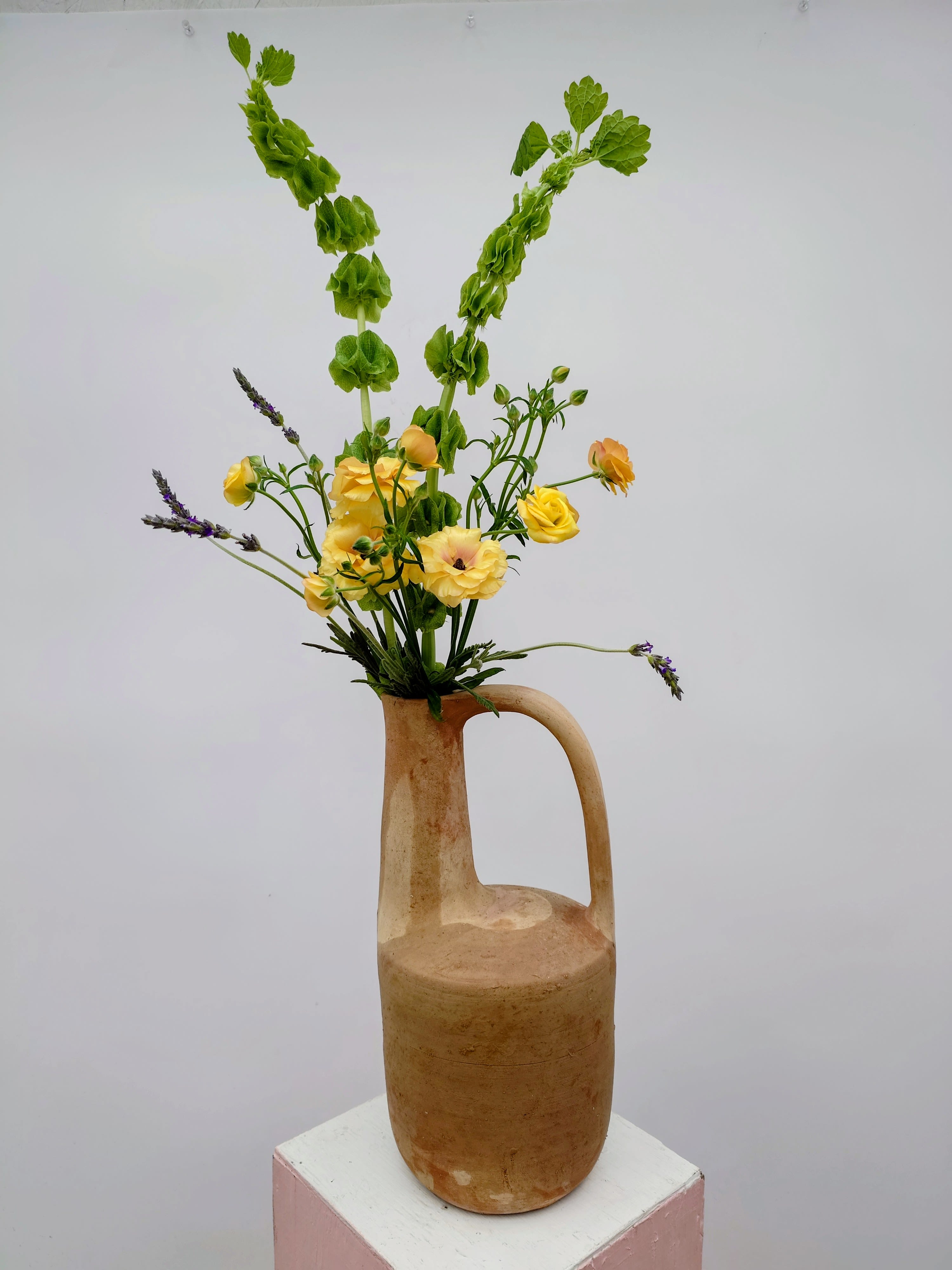 Juno Ascending - A sculptural floral arrangement designed in a tall, long-necked clay pitcher, Juno Ascending emphasizes line, movement, and negative space.   *Flowers featured may vary but will always be premium blooms of equal or higher value. Vessel is not water-tight; as such, flowers come in water tubes. Remove from tubes and put in water within 24 hours to preserve freshness.