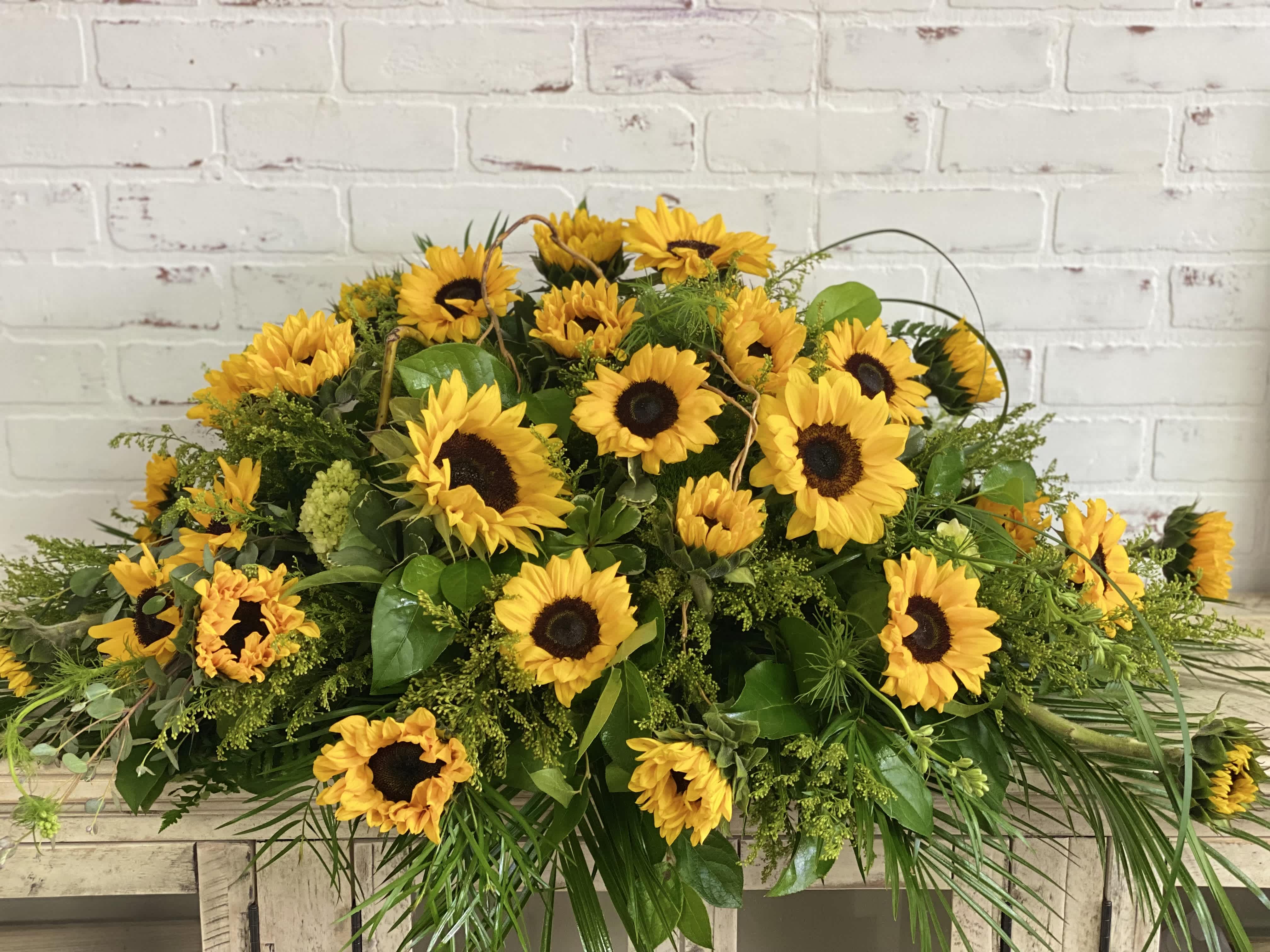 Large sunflower arrangement with greenery on a wooden table
