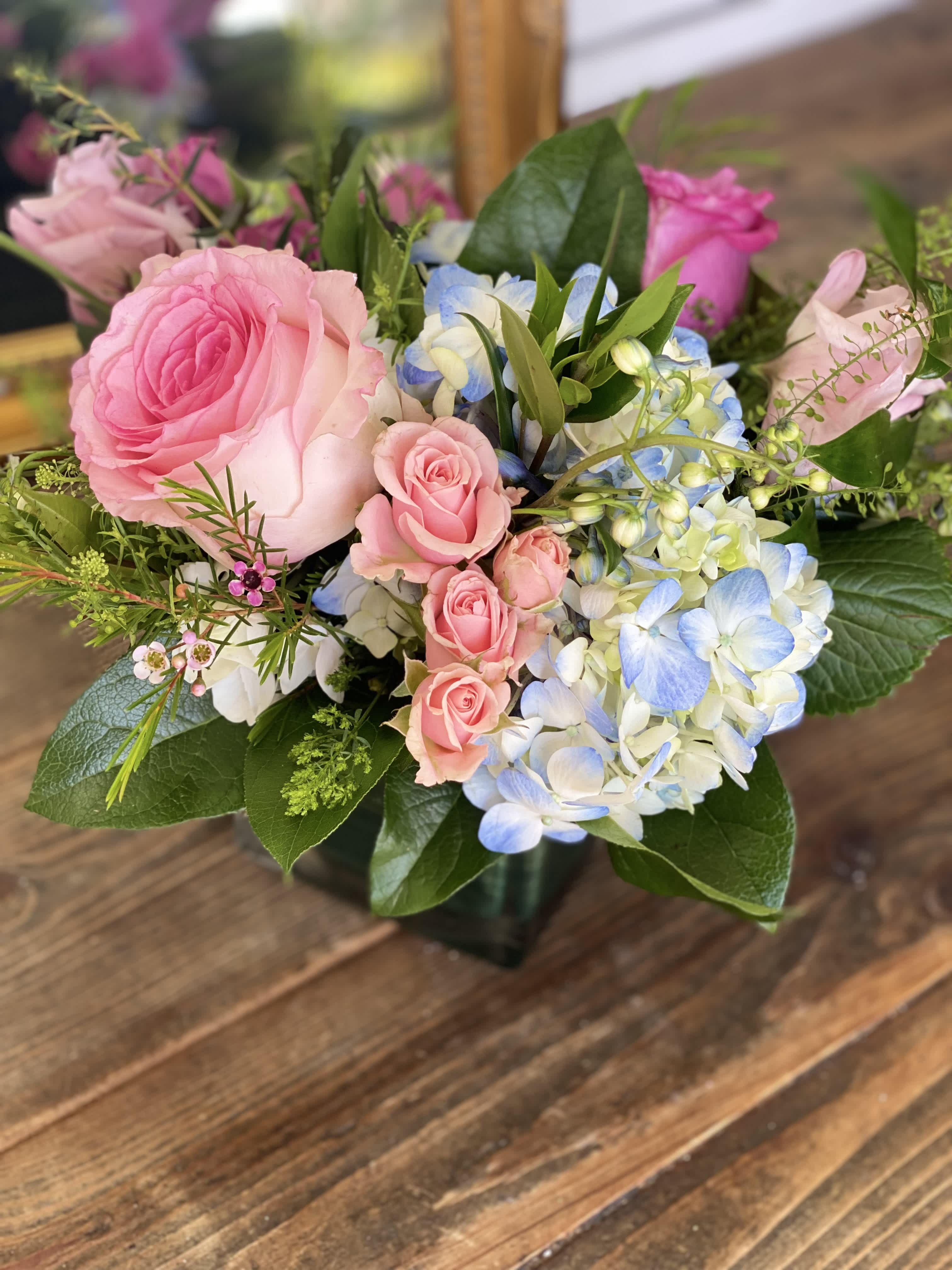 Pink roses and blue-white hydrangeas in a glass vase