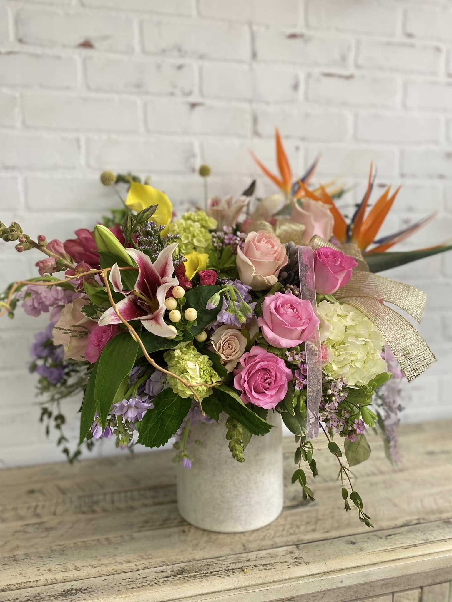 Mixed bouquet of pink roses, lilies, and hydrangeas in a white vase