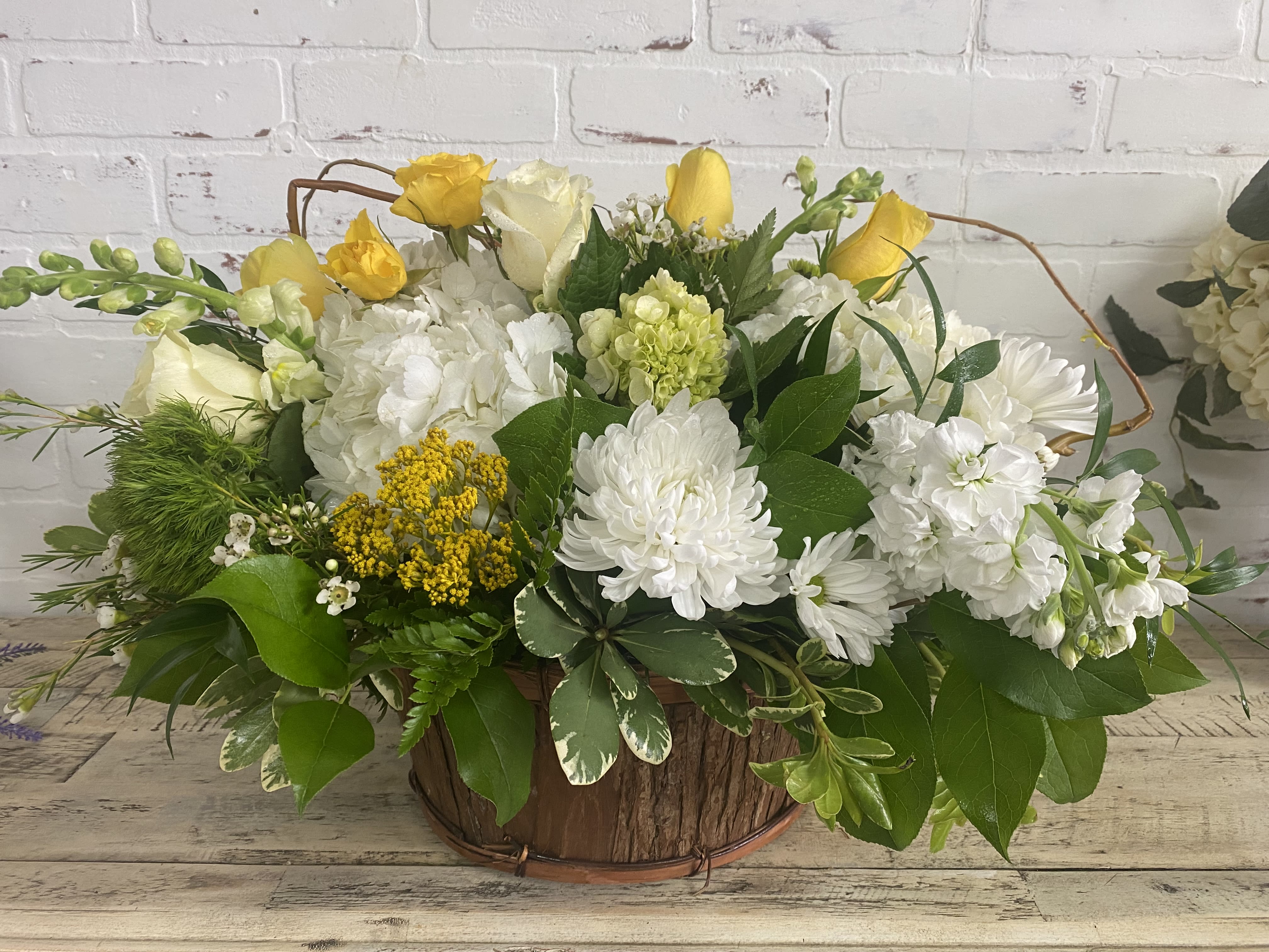 Yellow and white floral arrangement in a rustic wooden basket