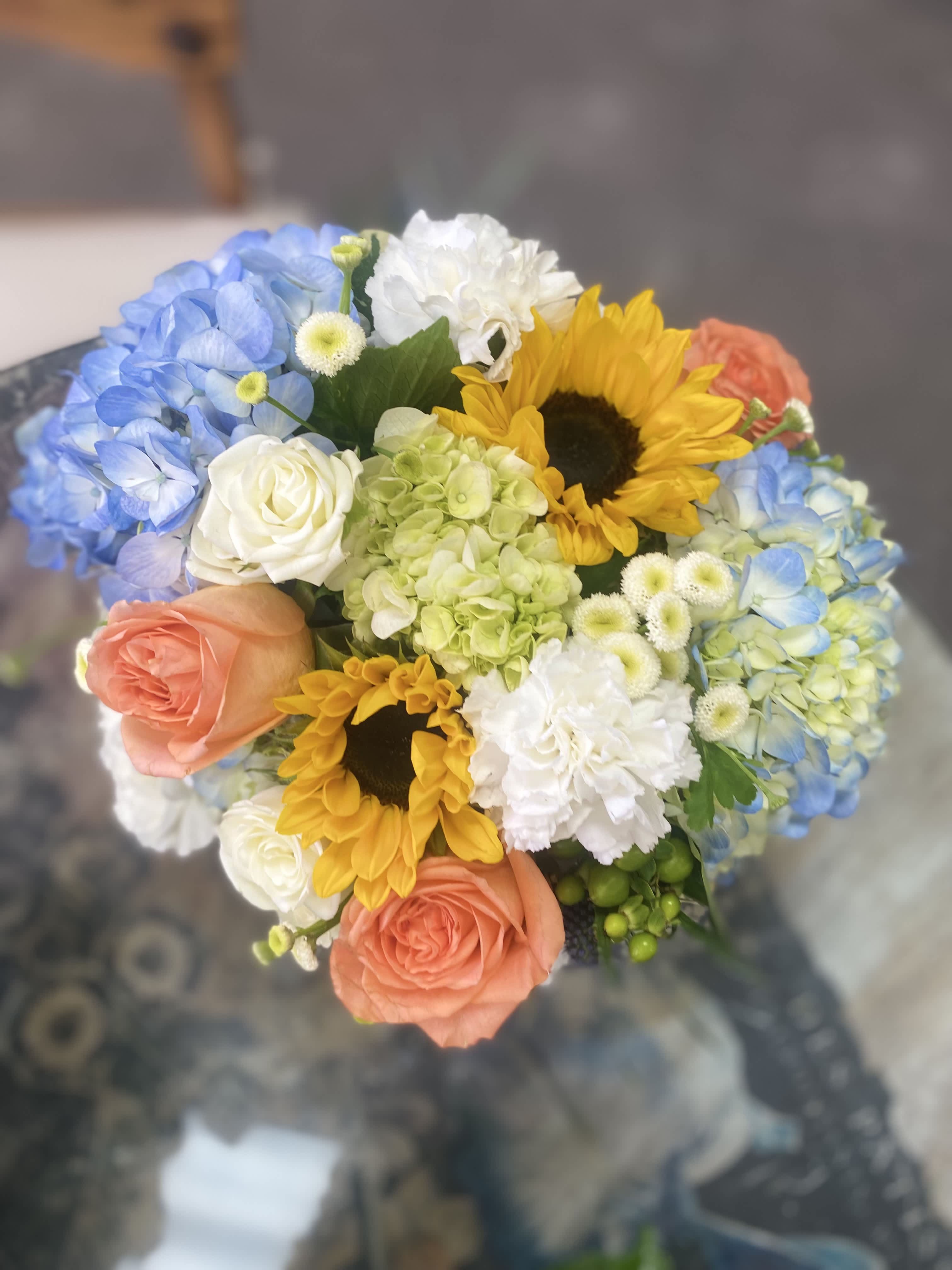 Bouquet of blue hydrangeas, sunflowers, and peach roses
