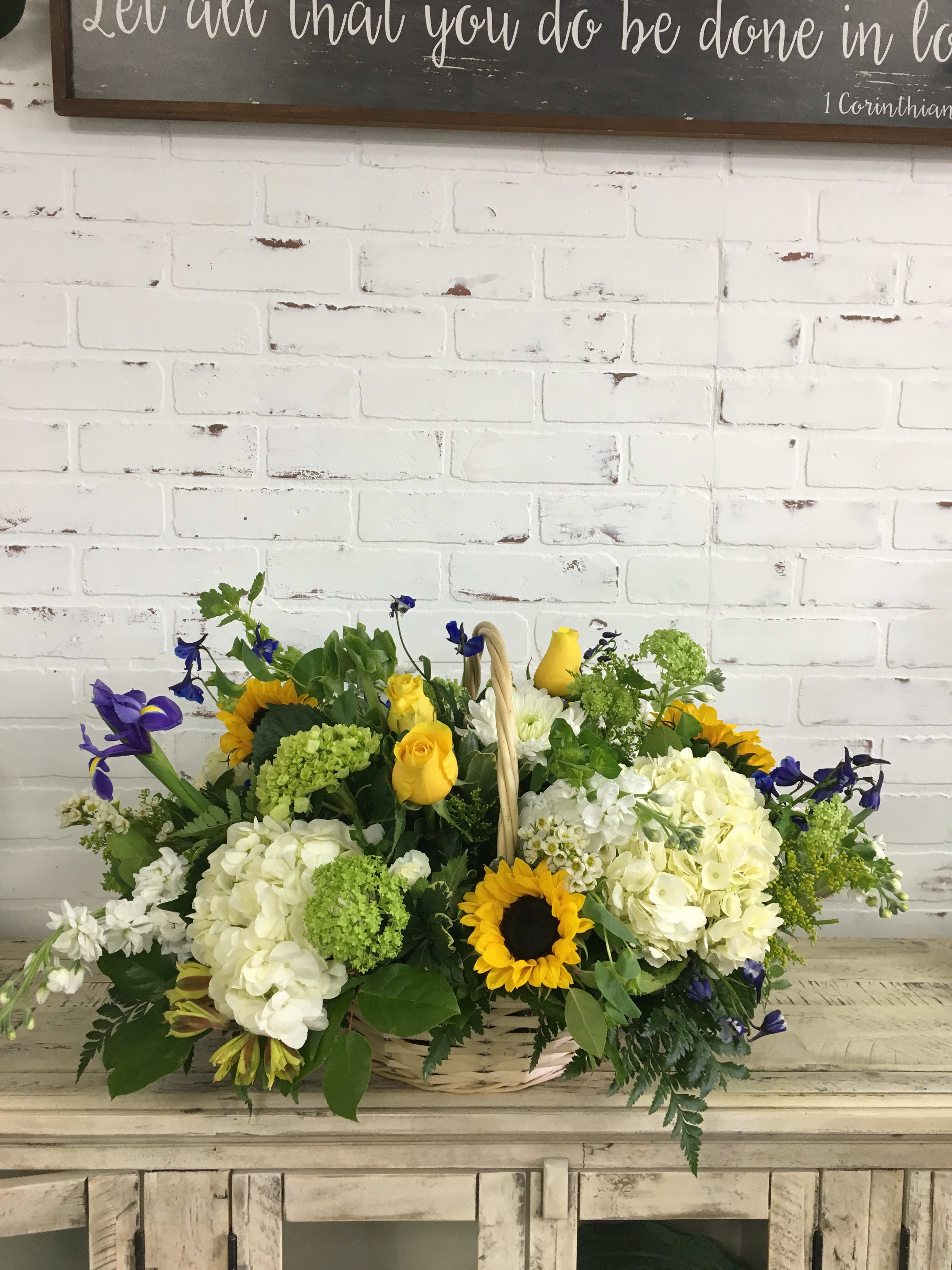 Basket of yellow, white, and blue flowers on a rustic table