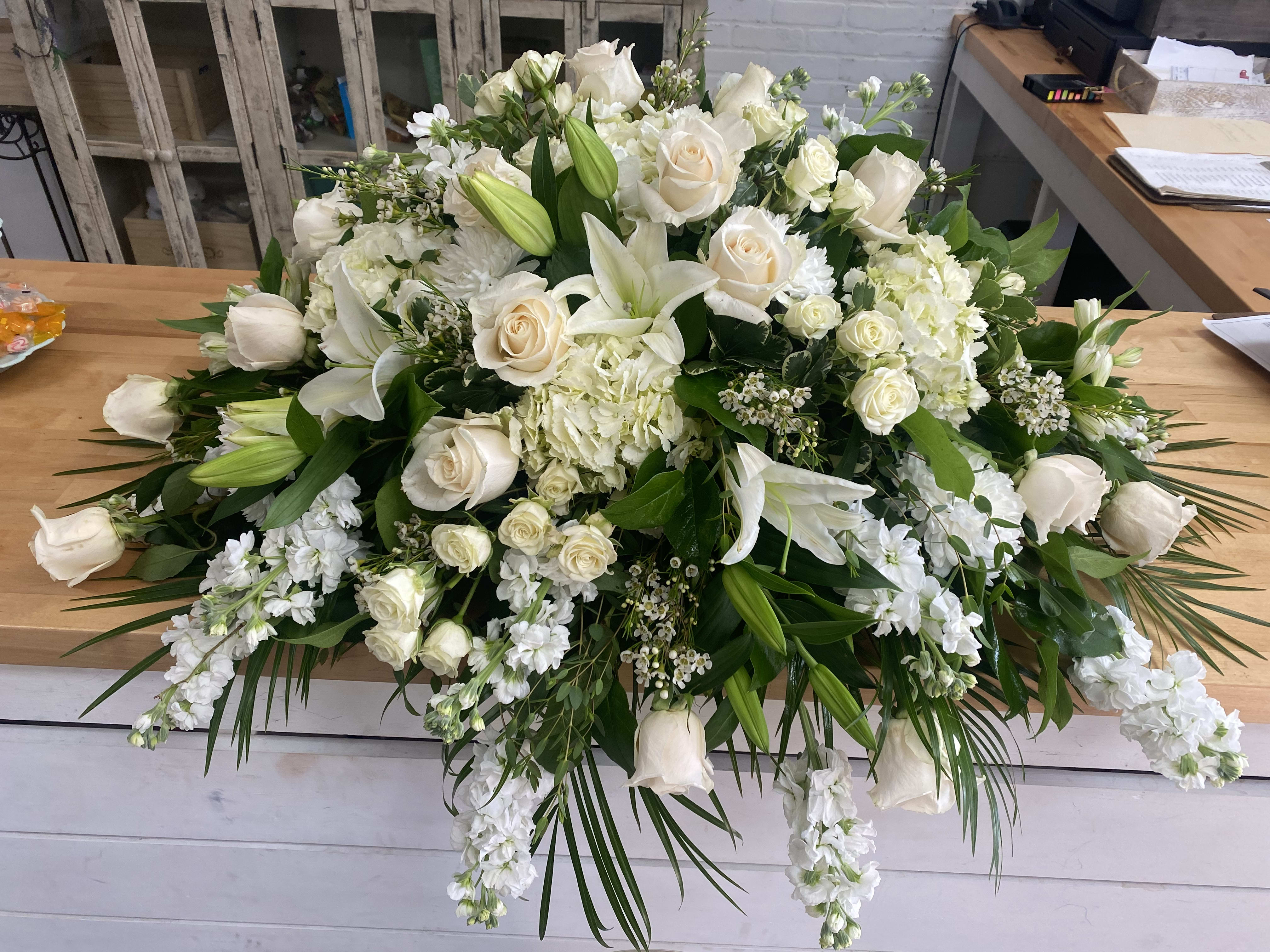 Large white floral arrangement with roses and lilies on a table