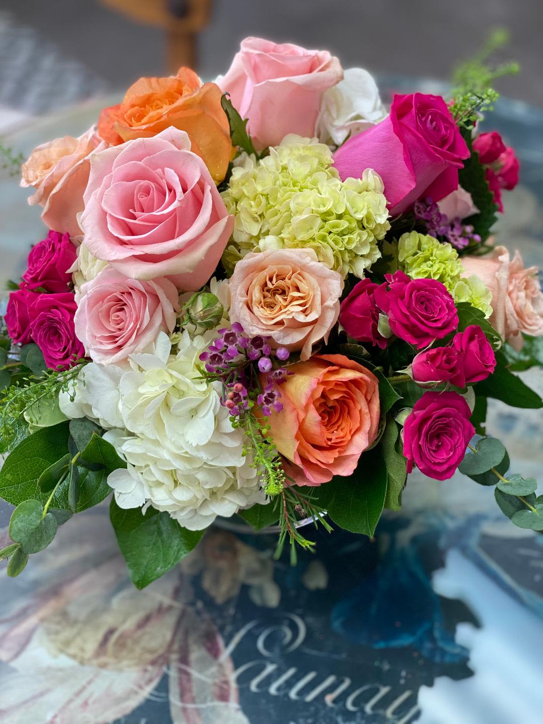 Bouquet of pink, orange, and white roses with pale hydrangeas