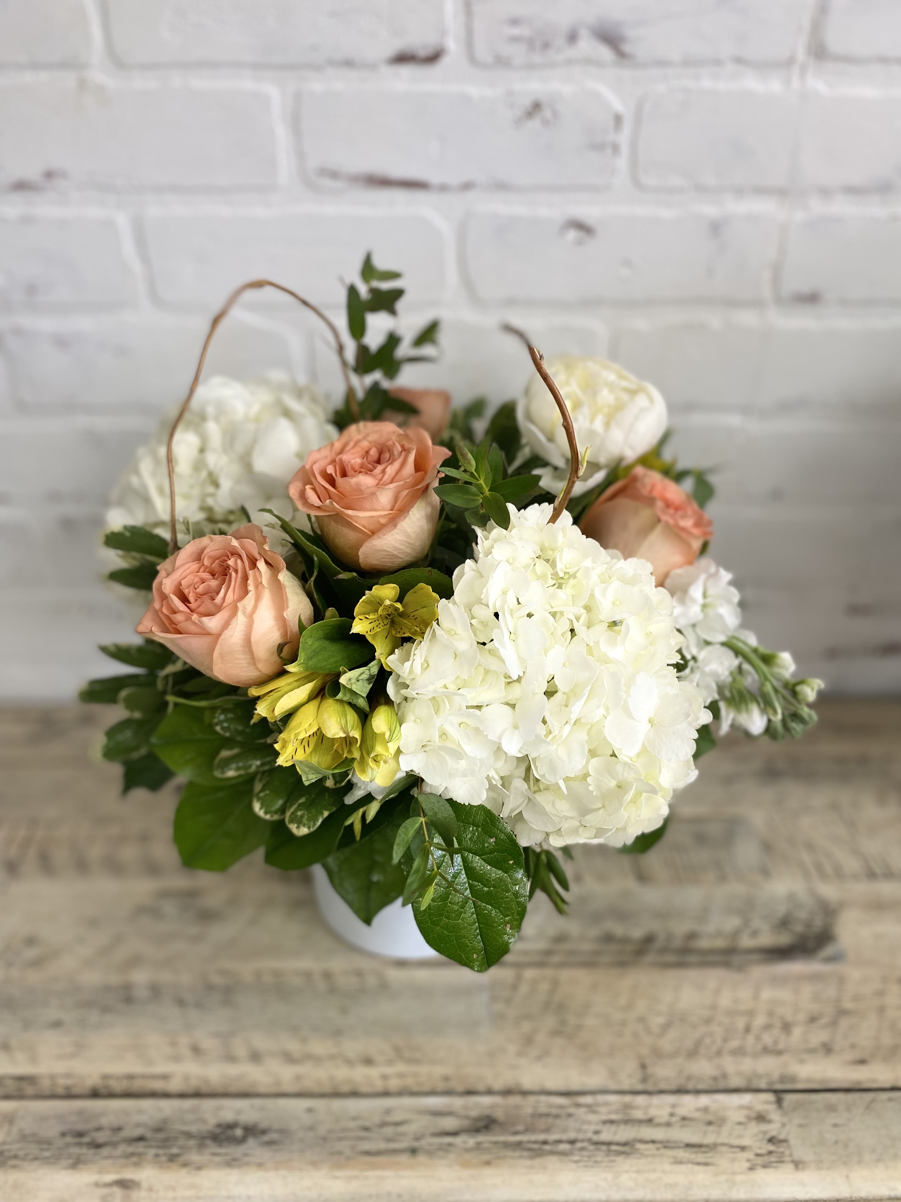 Peach roses and white hydrangea in a white container