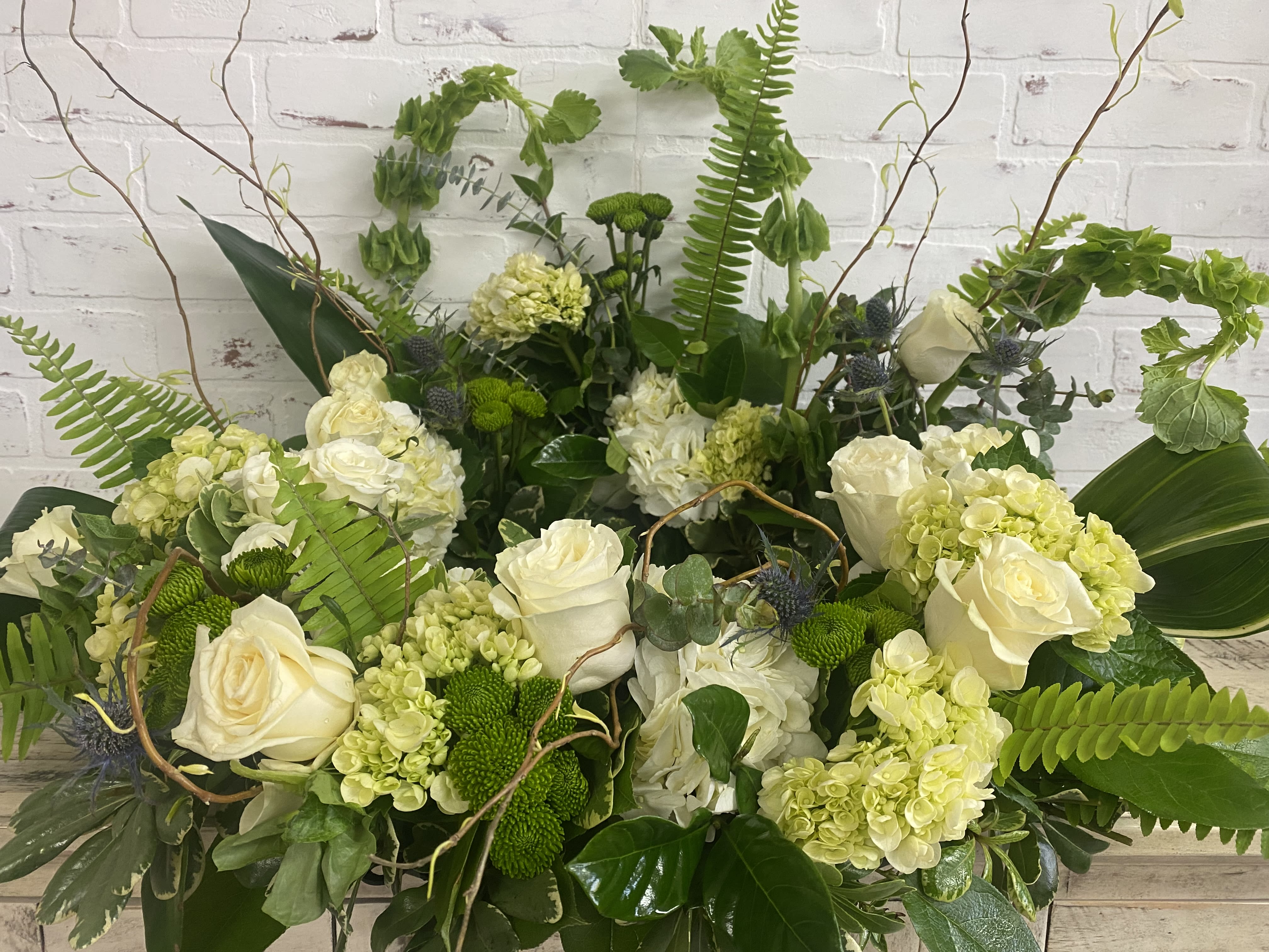Large green and white floral arrangement with roses and hydrangeas