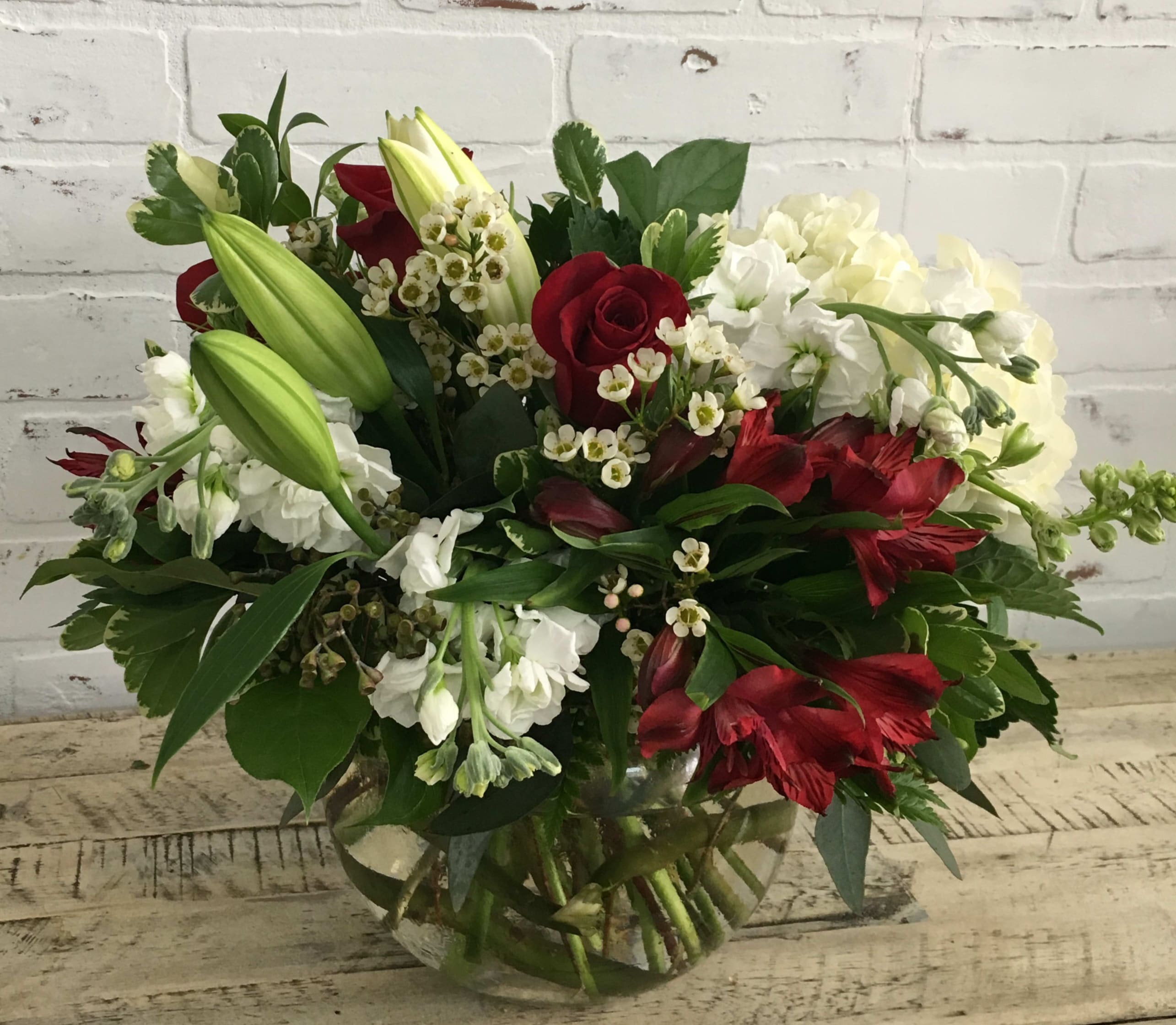 Bouquet of red roses, white lilies, and white hydrangeas in a glass vase