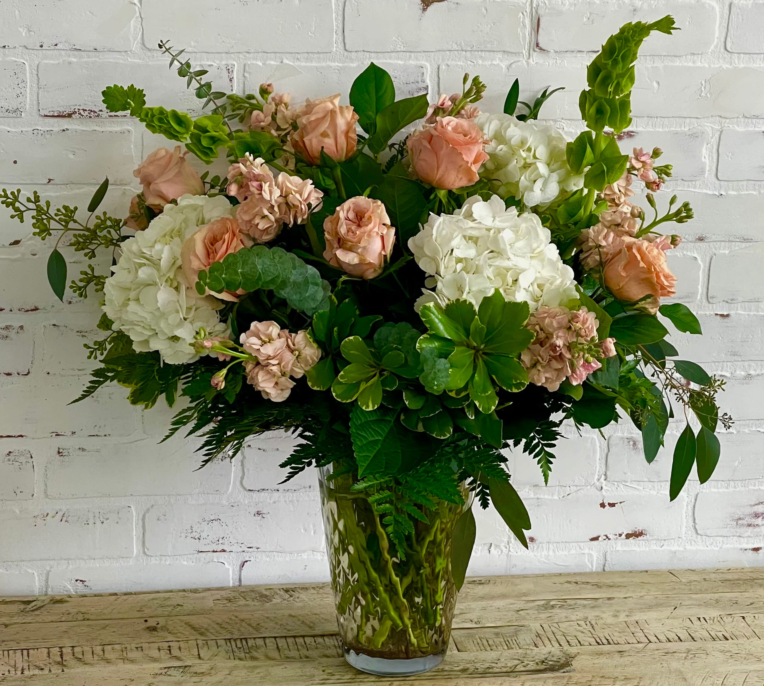 Peach roses and white hydrangeas in a glass vase