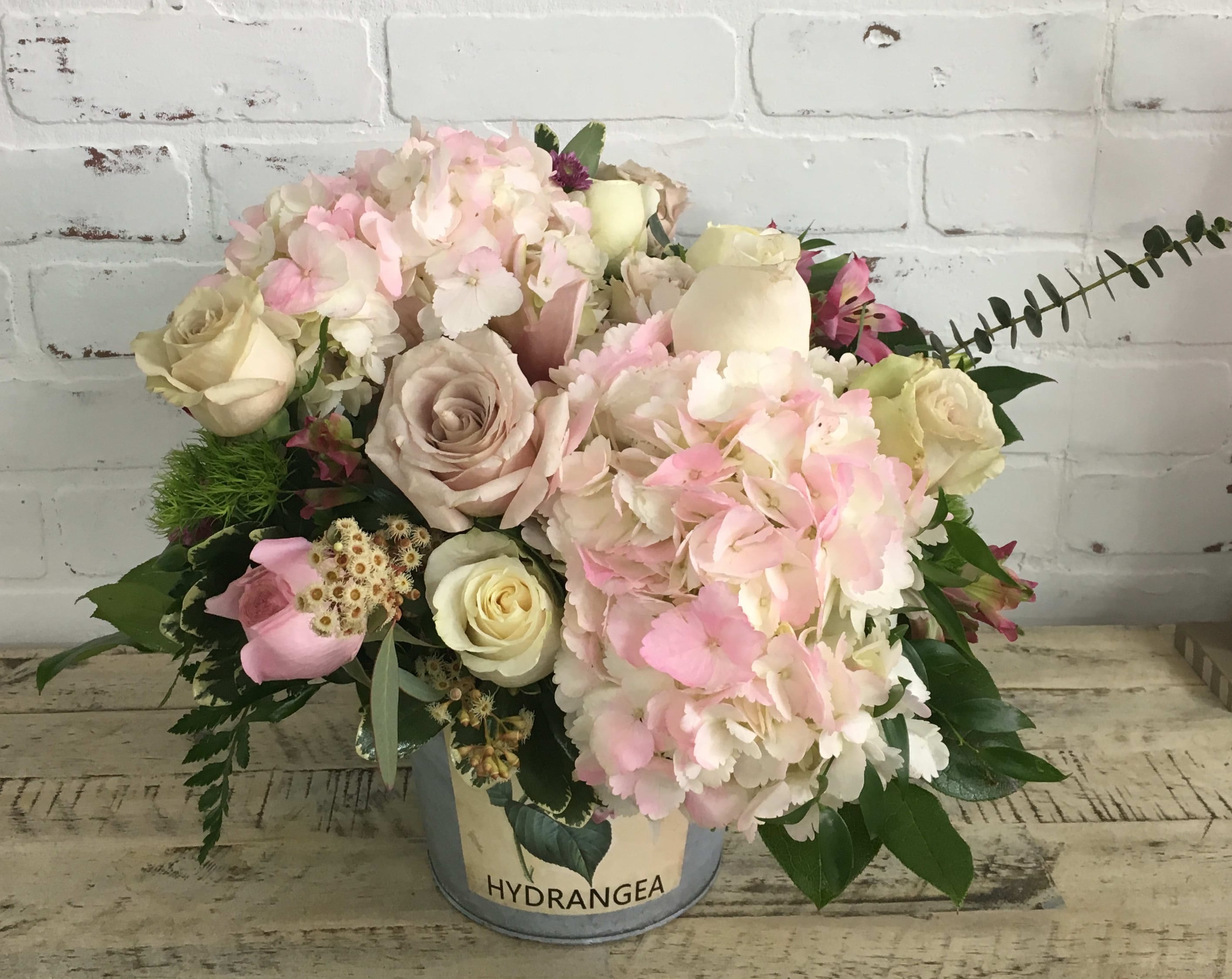 Pink and cream bouquet in a metal bucket with hydrangeas and roses