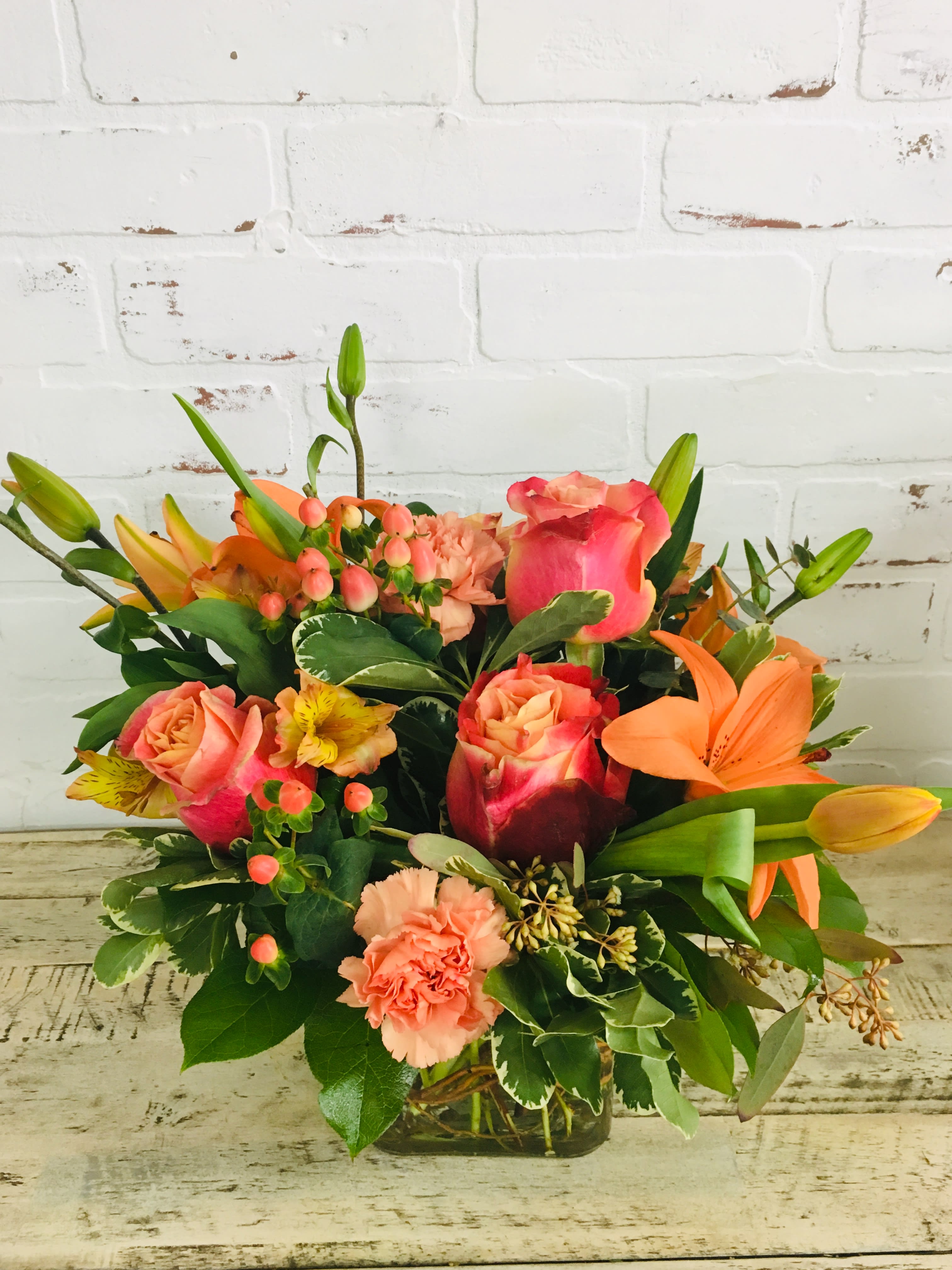 Mixed bouquet of pink roses, lilies, and carnations in a glass vase