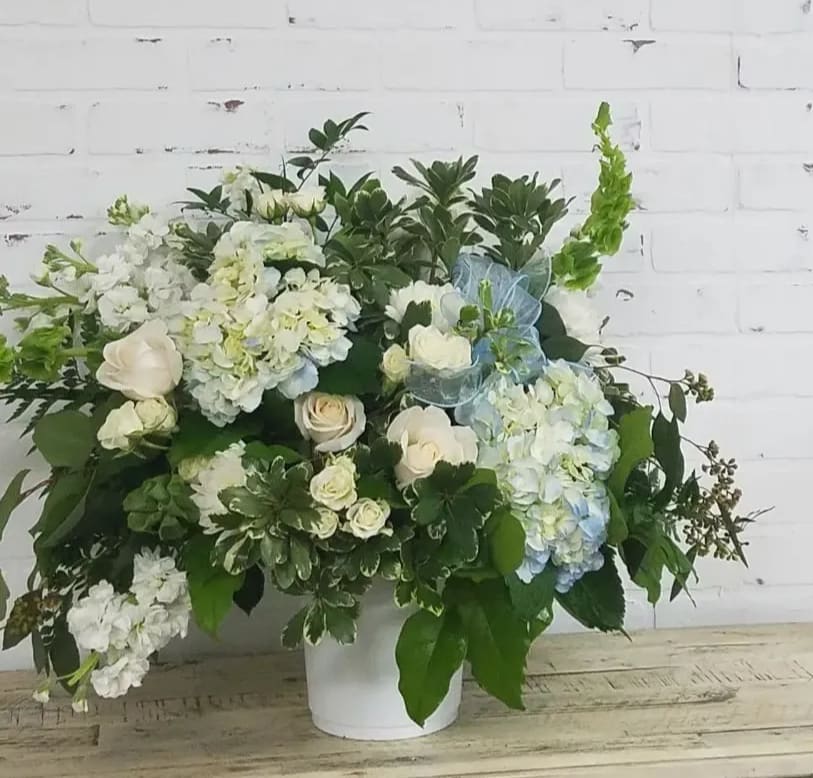 White and pale blue floral arrangement in a white vase