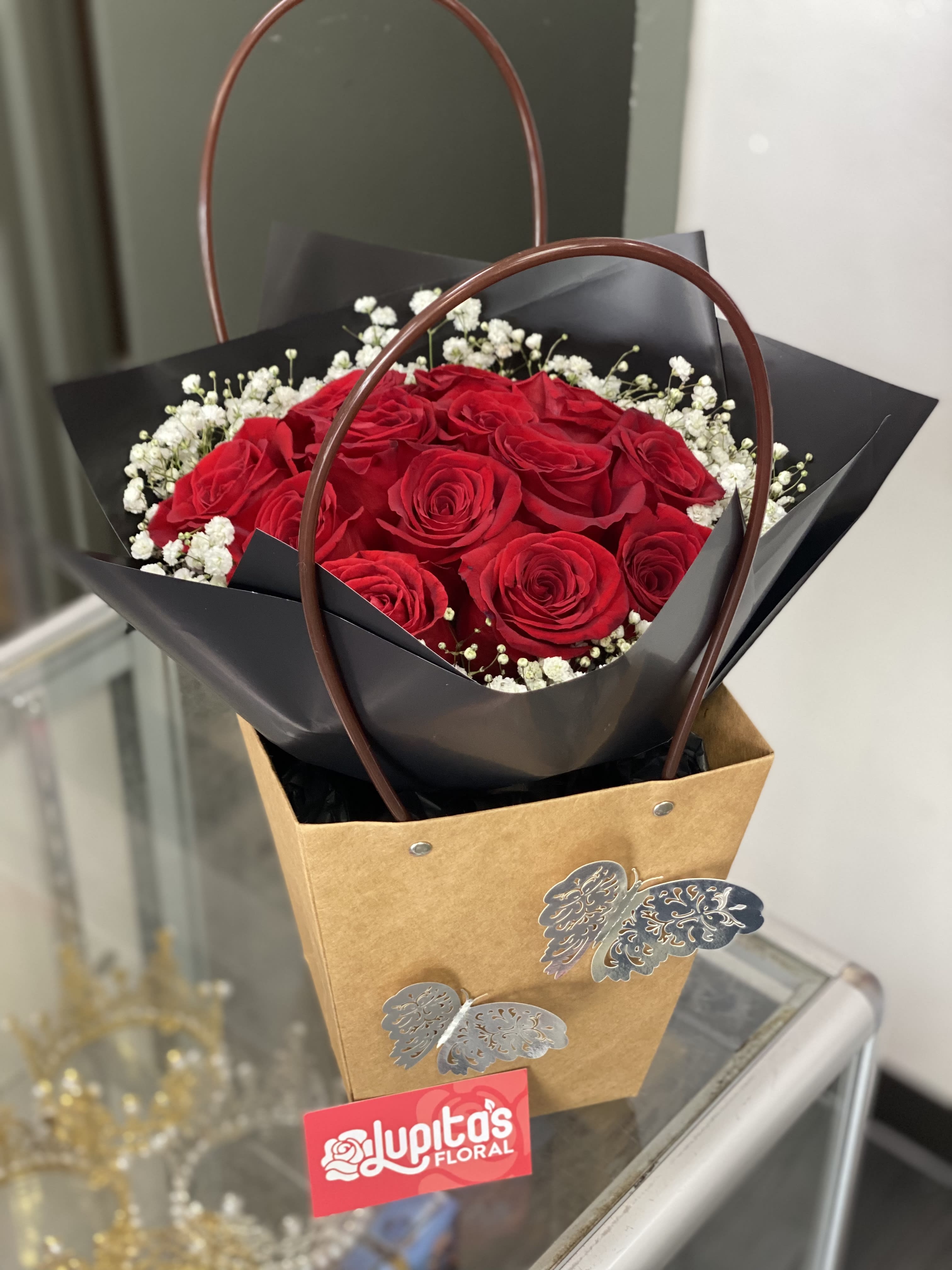 Red rose bouquet with baby's breath in a brown gift bag