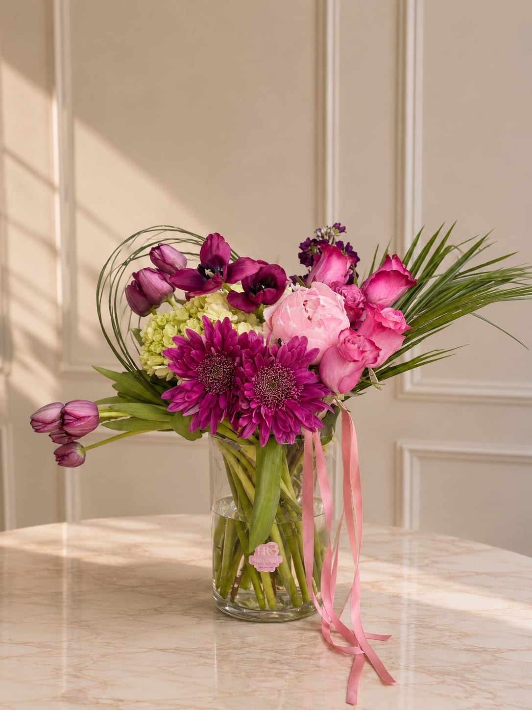 Tulip Kiss - A modern arrangement featuring tulips, roses, hydrangeas, and seasonal blooms in rich pink and plum tones.