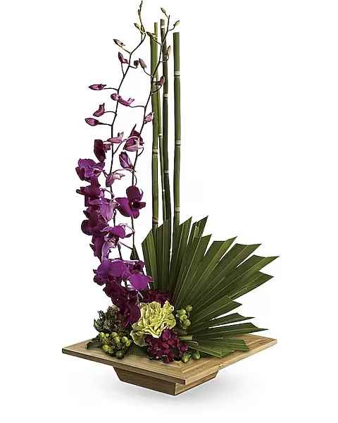 Tall orchid arrangement with purple blooms and green bamboo in a wooden base