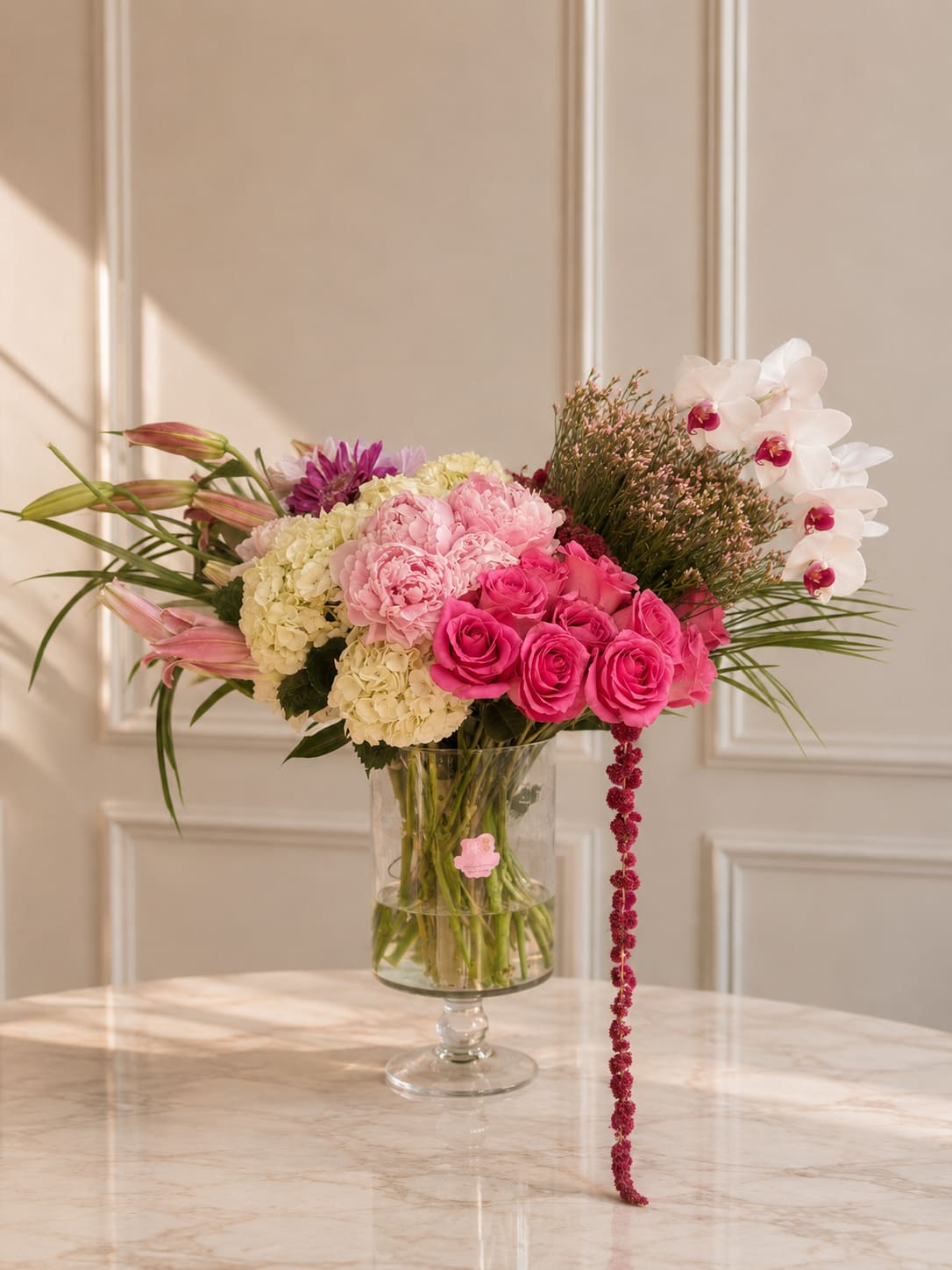 Rosé Orchid Bloom - A luxurious arrangement featuring orchids, roses, hydrangeas, lilies, and seasonal blooms in elegant blush and ivory tones.