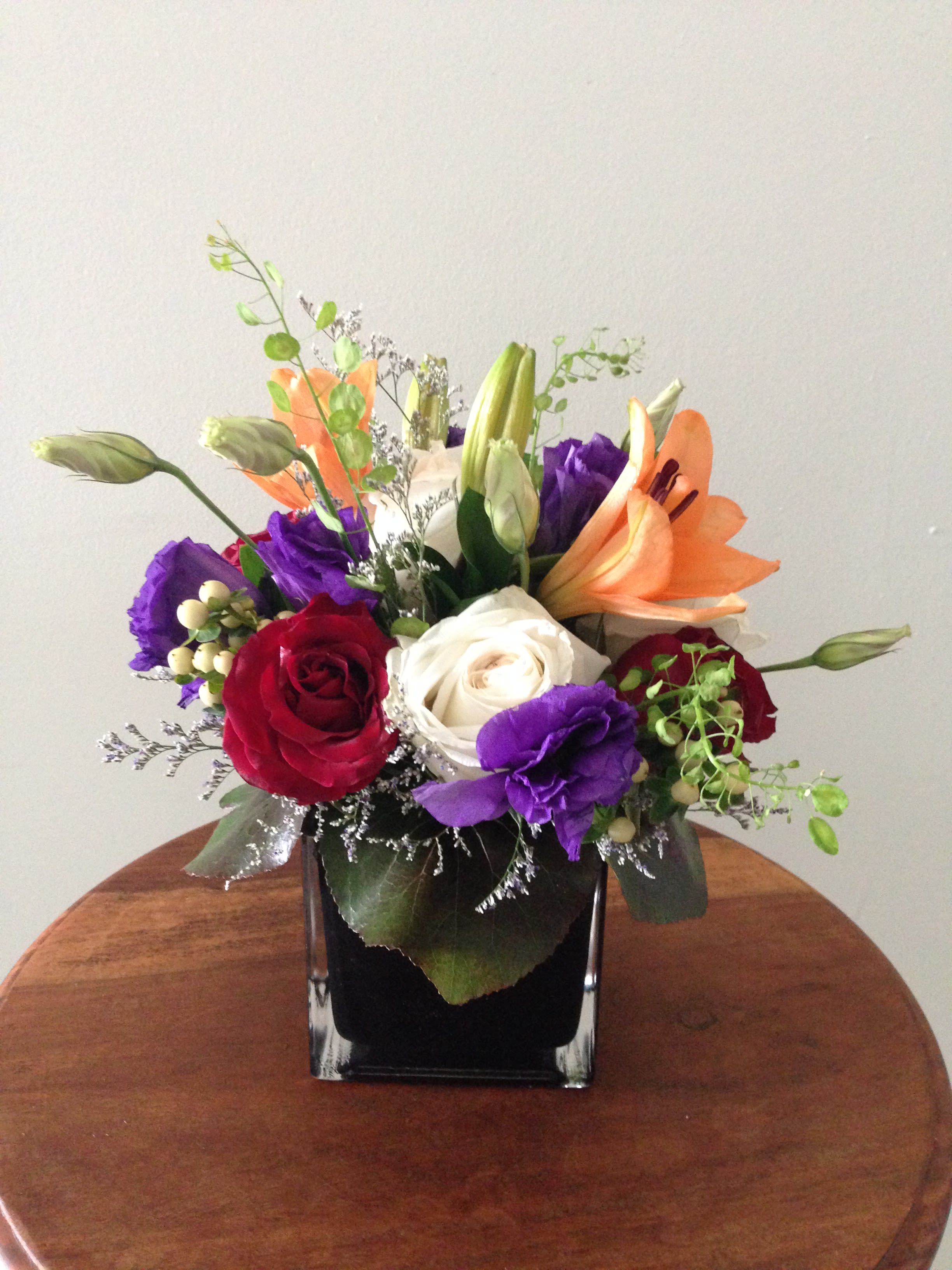 Mixed bouquet of roses and lilies in a black square vase