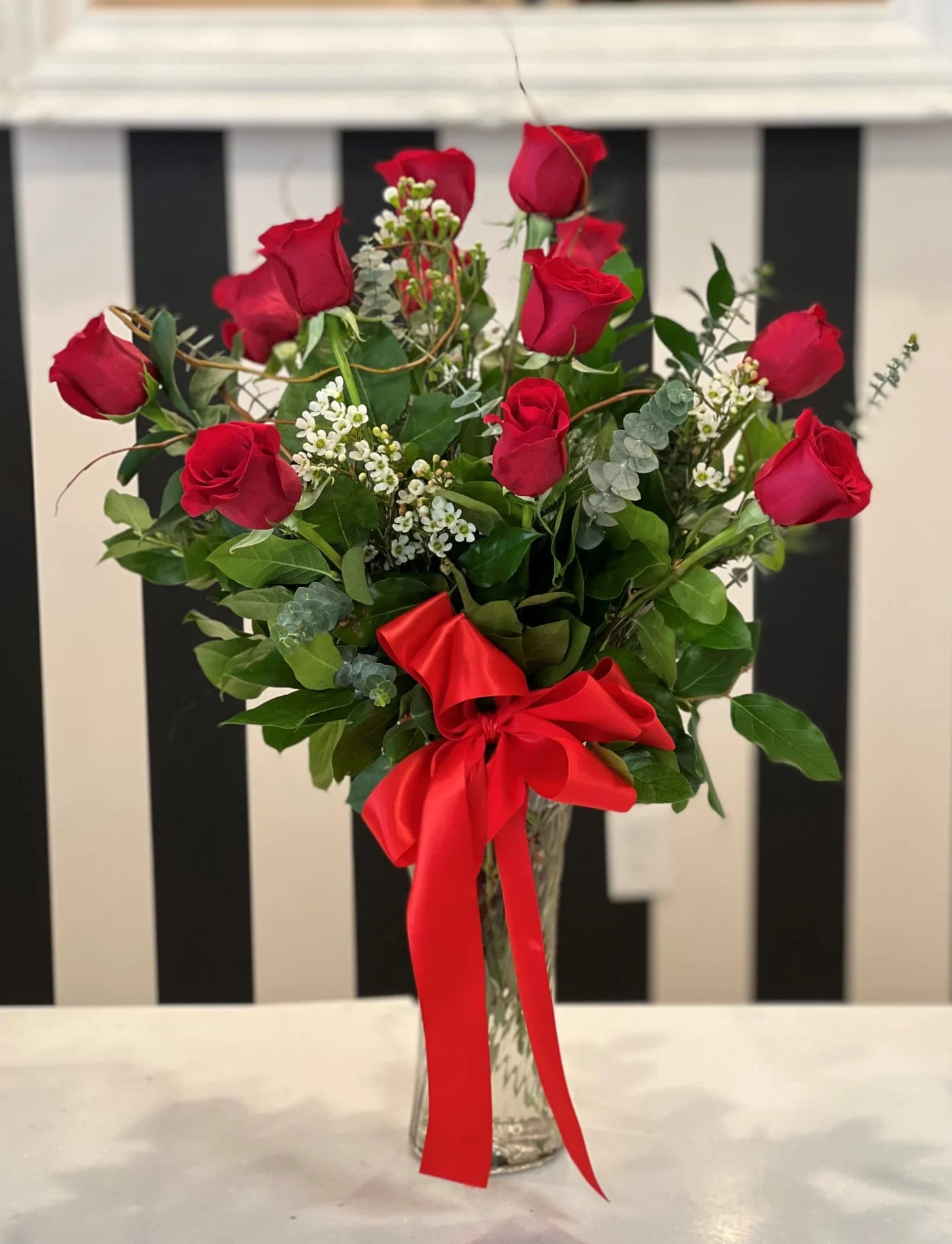 Red roses arranged in a clear glass vase with a red ribbon