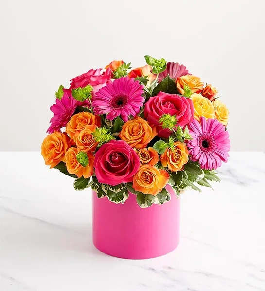 Bouquet of pink and orange roses with pink gerbera daisies in a pink vase