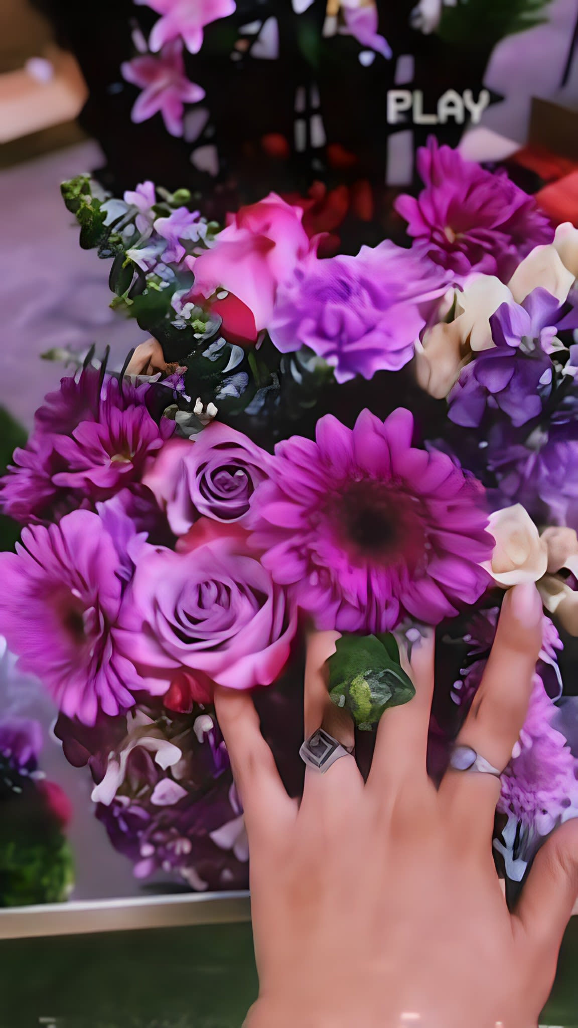 Hand holding a bouquet of purple flowers and roses