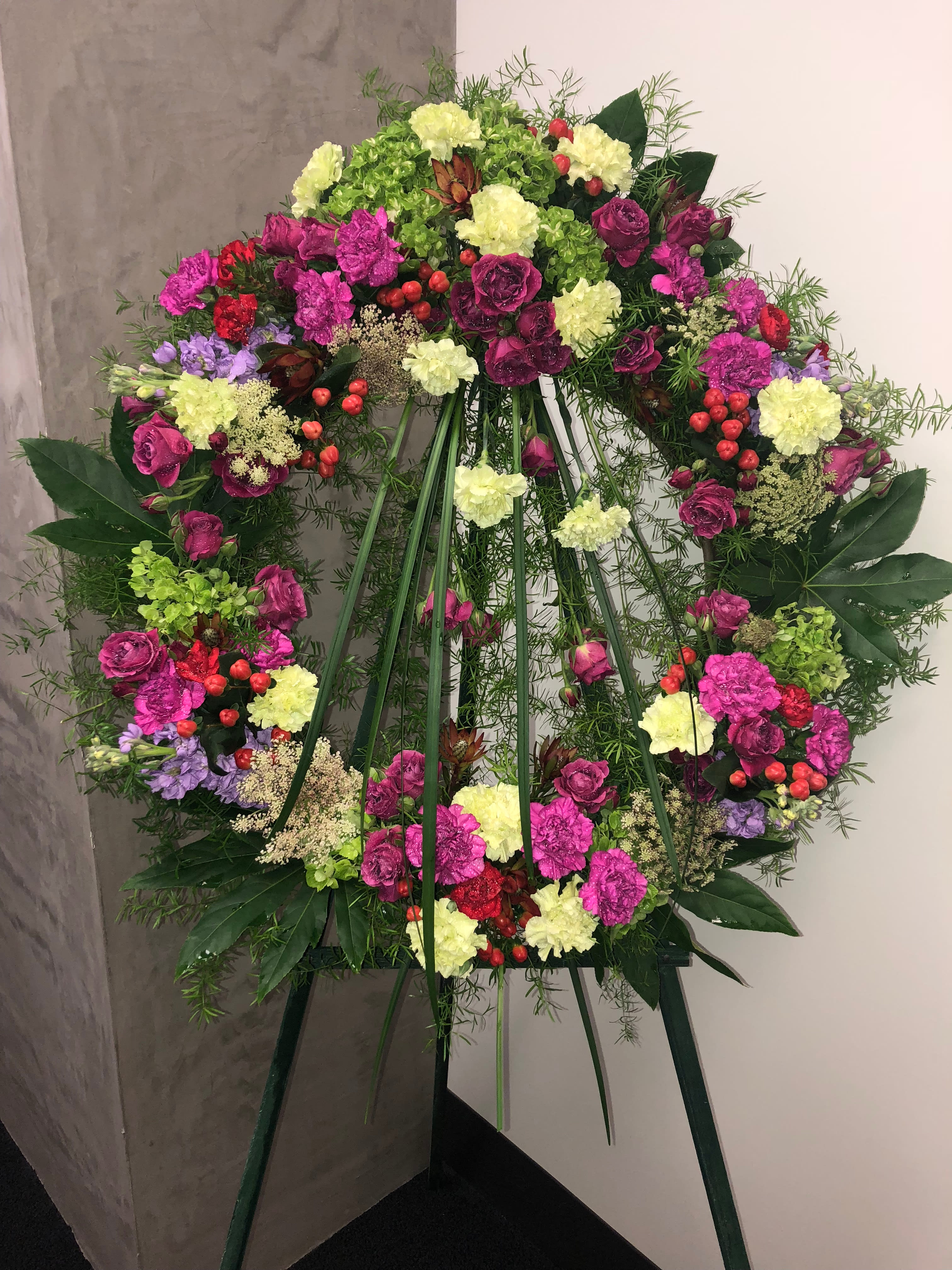 Large floral wreath on an easel with pink, yellow, and purple blooms