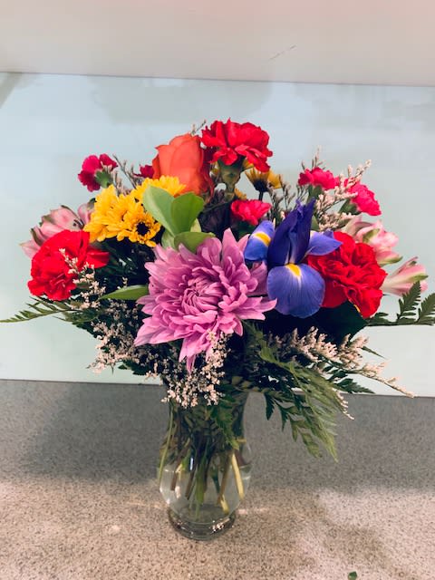 Mixed bouquet of colorful flowers in a clear glass vase