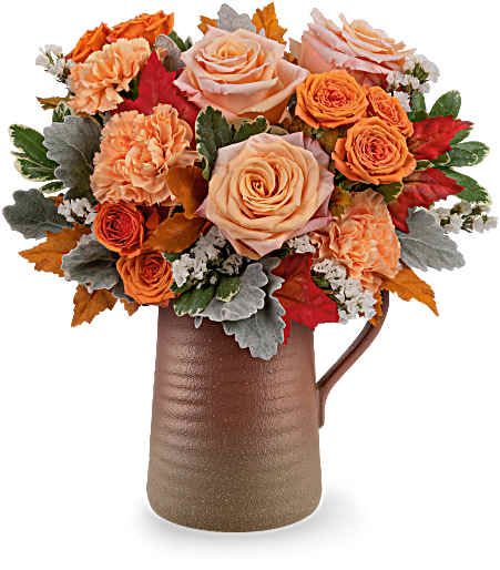 Orange and peach roses arranged in a brown pitcher vase