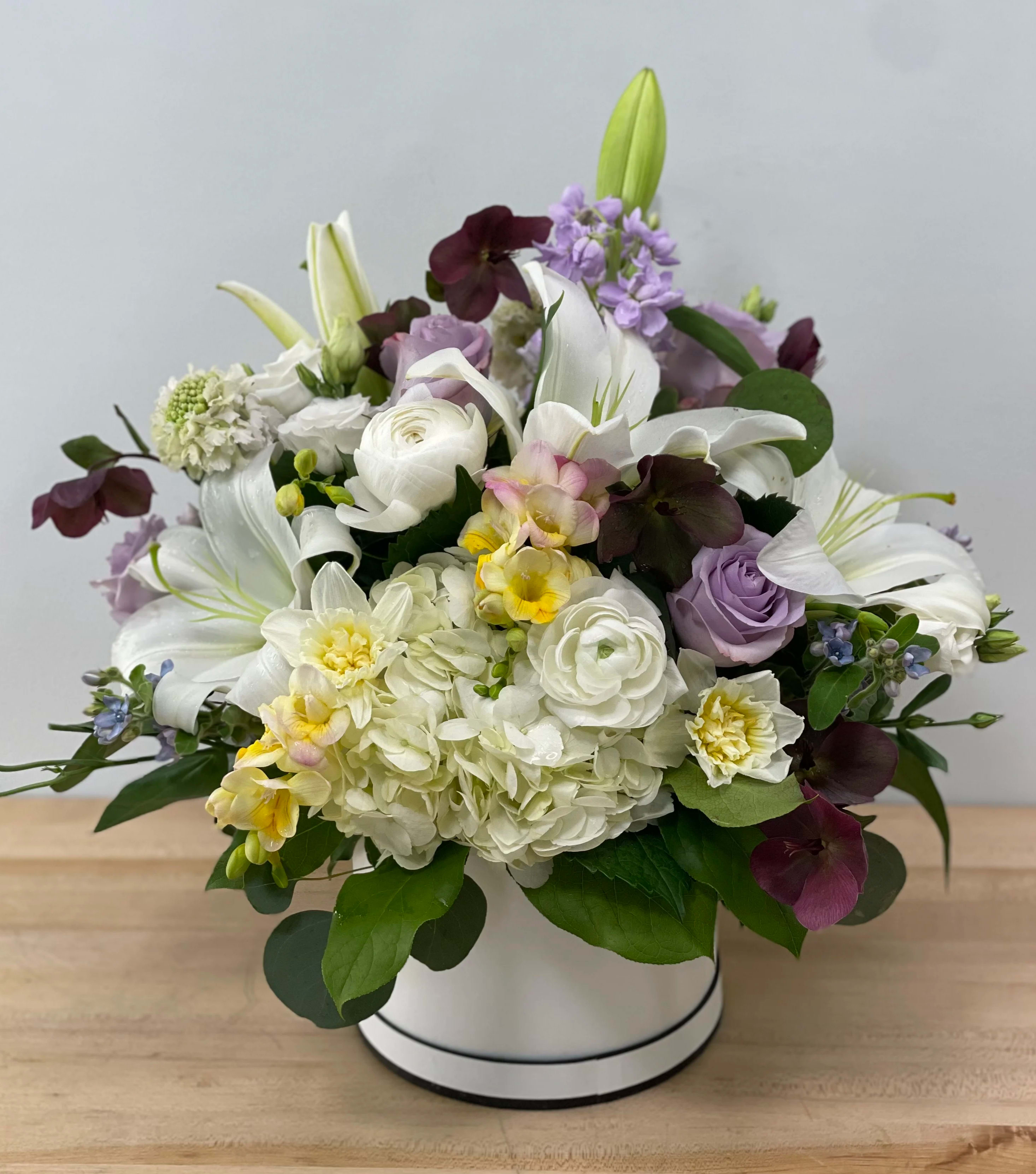 Mixed bouquet of white lilies, roses, and hydrangeas in a white hat box