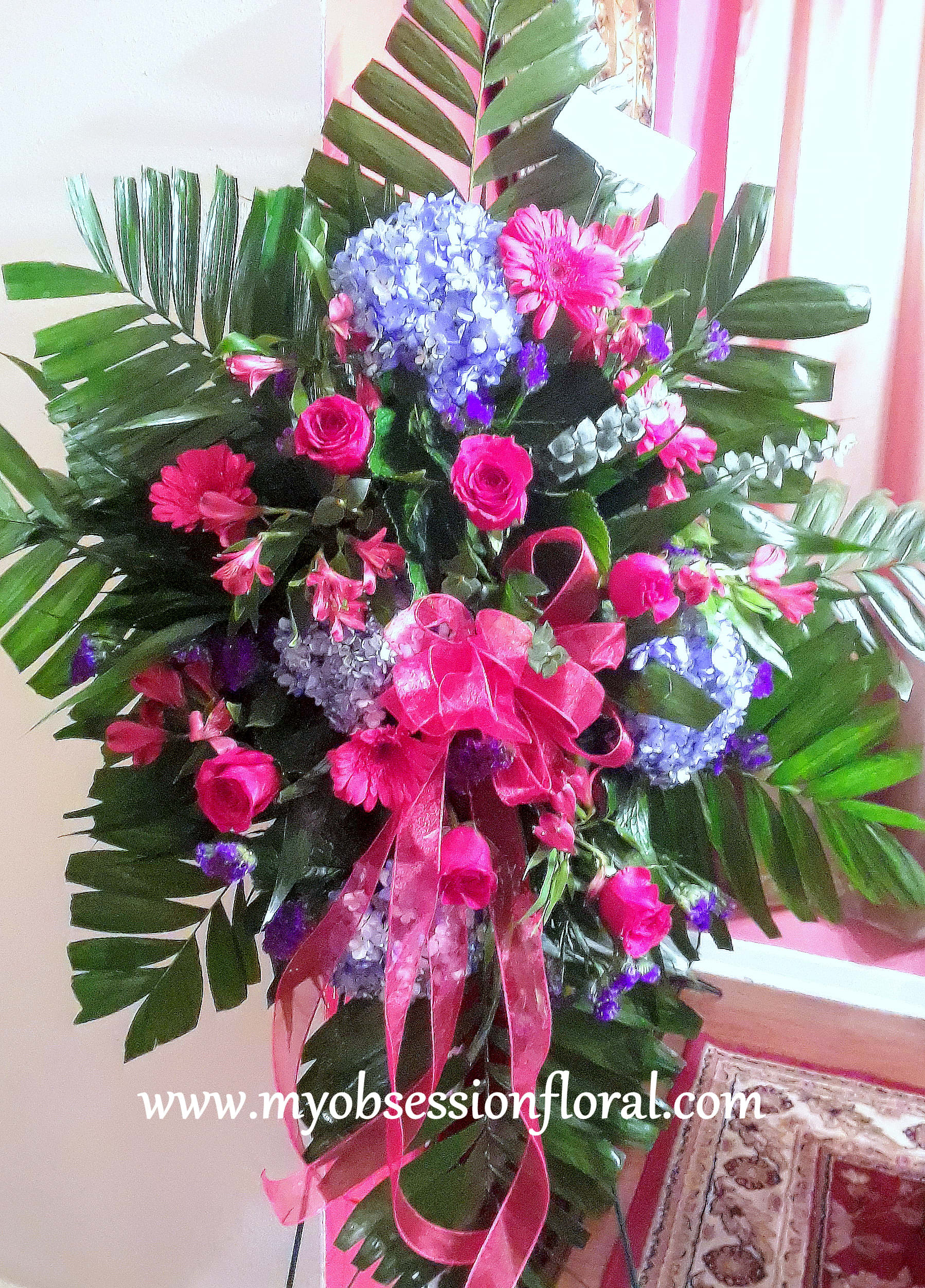 Large pink and blue floral standing arrangement with ribbon