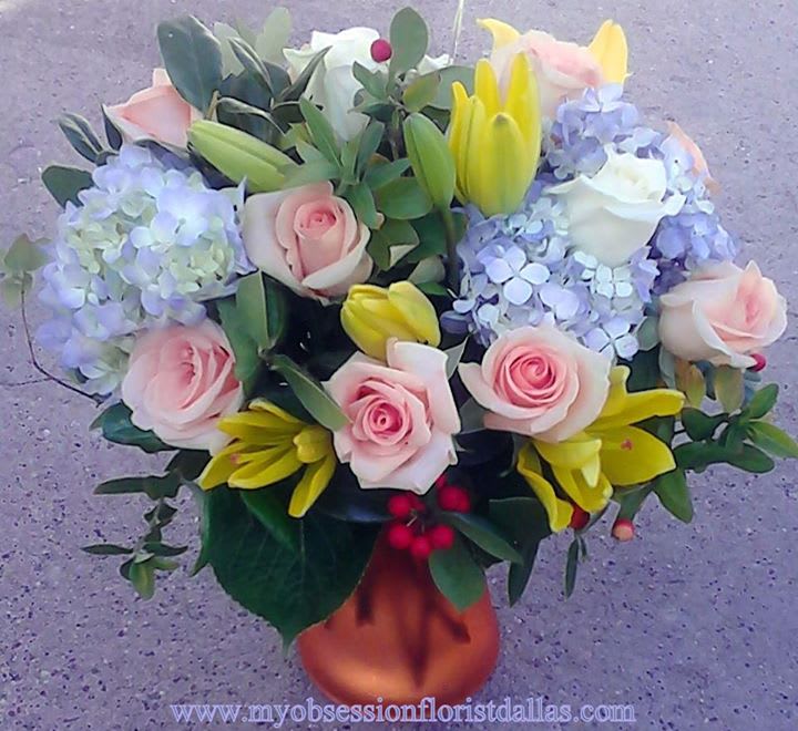 Bouquet of pink roses, yellow lilies, and blue hydrangeas in a vase