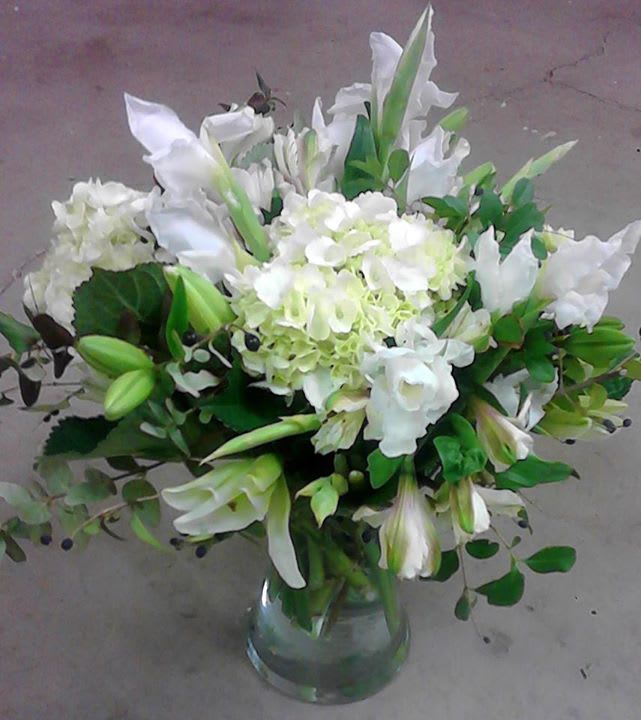 White lilies and hydrangeas arranged in a clear glass vase