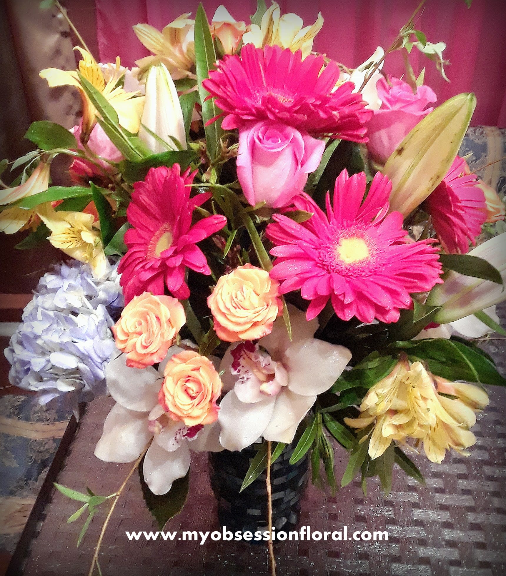 Mixed bouquet with pink gerbera daisies, roses, lilies, and orchids