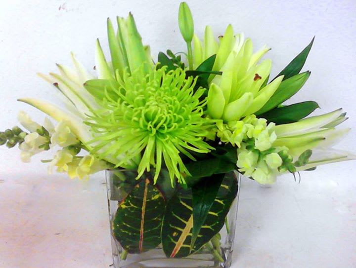 Green and white floral arrangement in a clear glass vase
