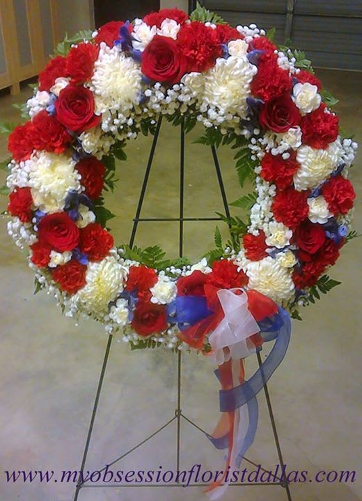 Heart-shaped floral wreath on a stand with red, white, and blue flowers