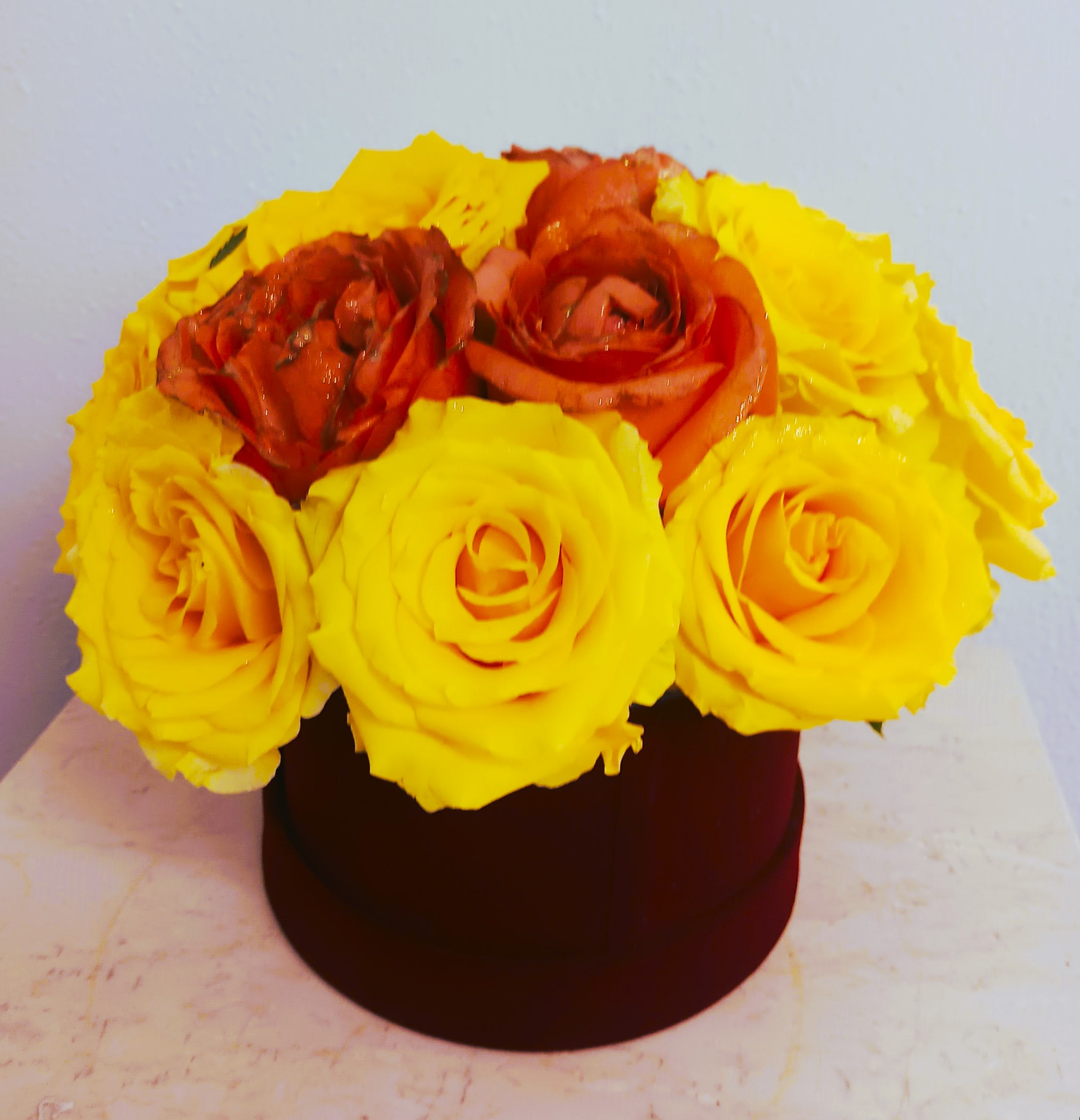 Yellow and orange roses arranged in a round box