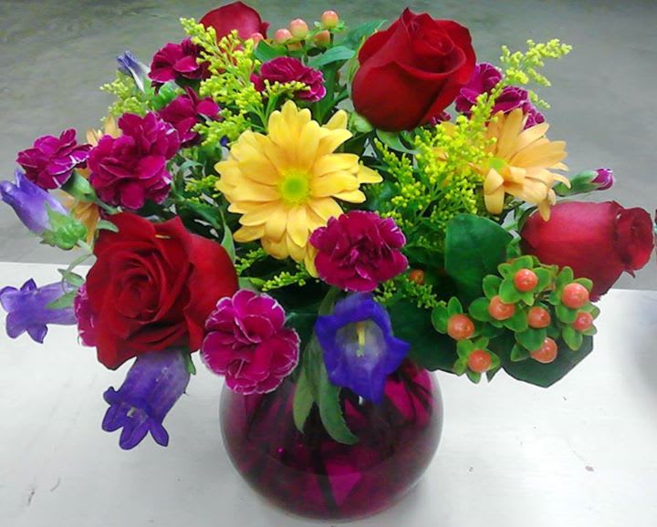 Mixed bouquet in a purple glass vase with red roses and yellow daisies