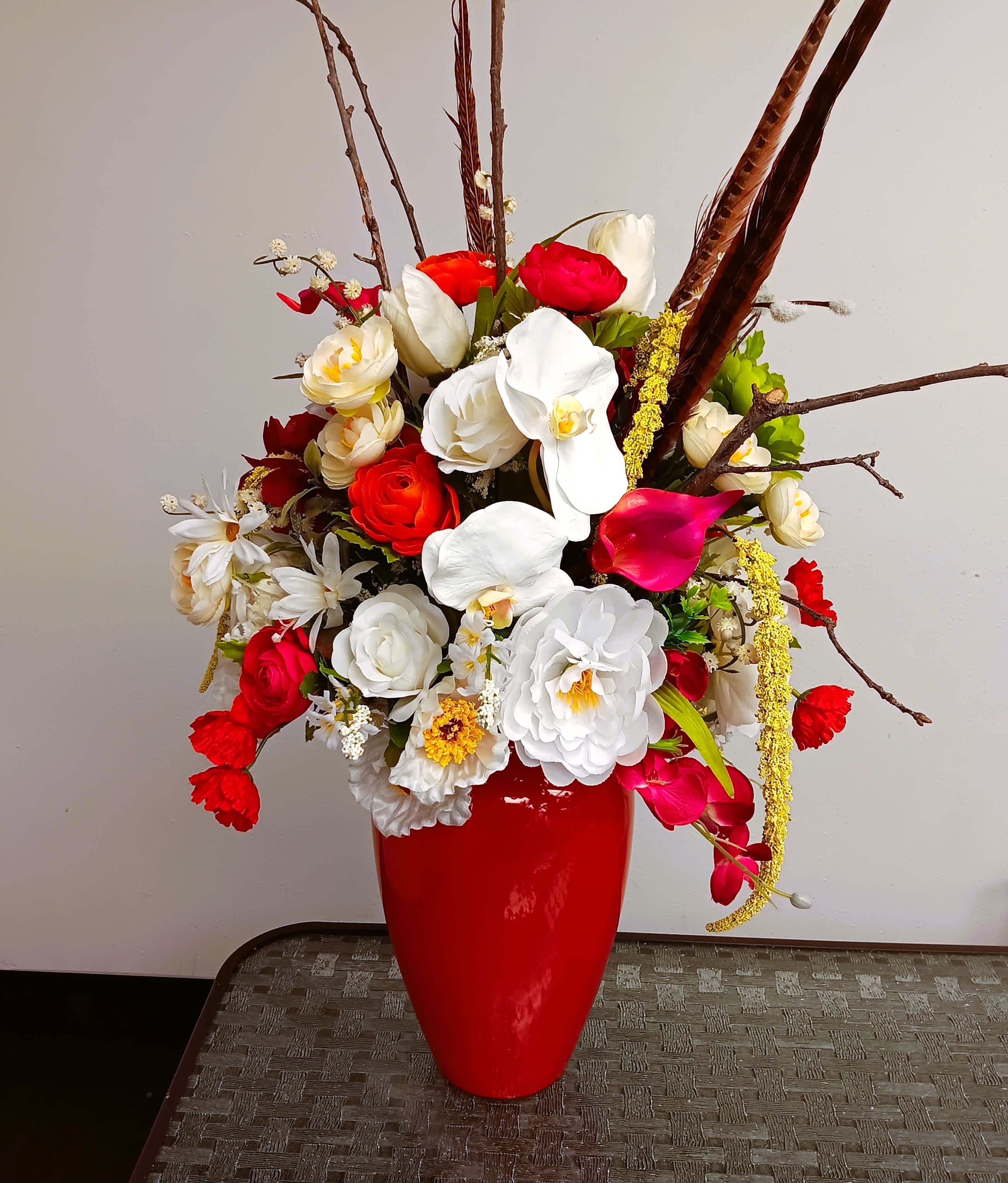 Red vase with a mixed bouquet of white, red, and pink flowers