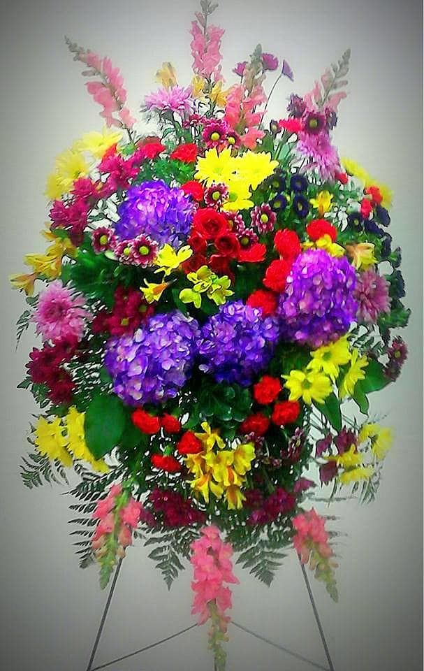 Large standing spray of mixed bright flowers on an easel