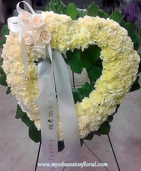 Heart-shaped white floral wreath with ribbon and roses