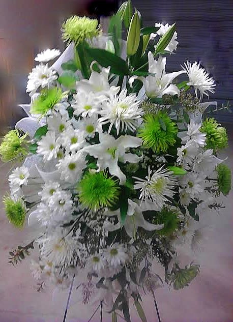 White and green funeral spray with lilies and daisies on a stand