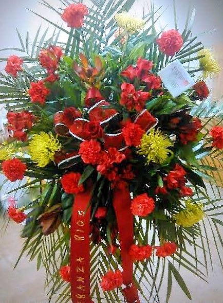 Tall red and yellow floral standing arrangement with ribbon streamers