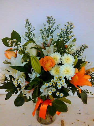 Bouquet of orange and white flowers in a glass vase with an orange ribbon