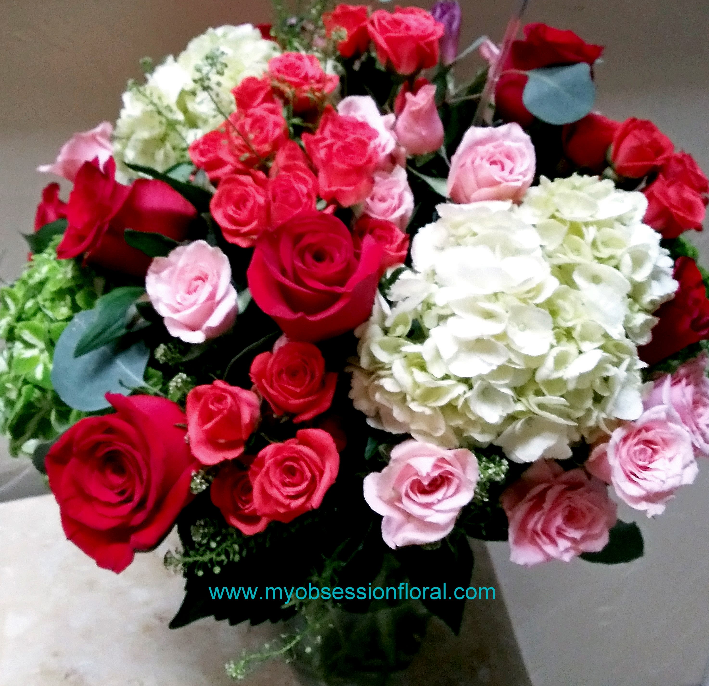 Bouquet of red, pink, and white roses with hydrangeas