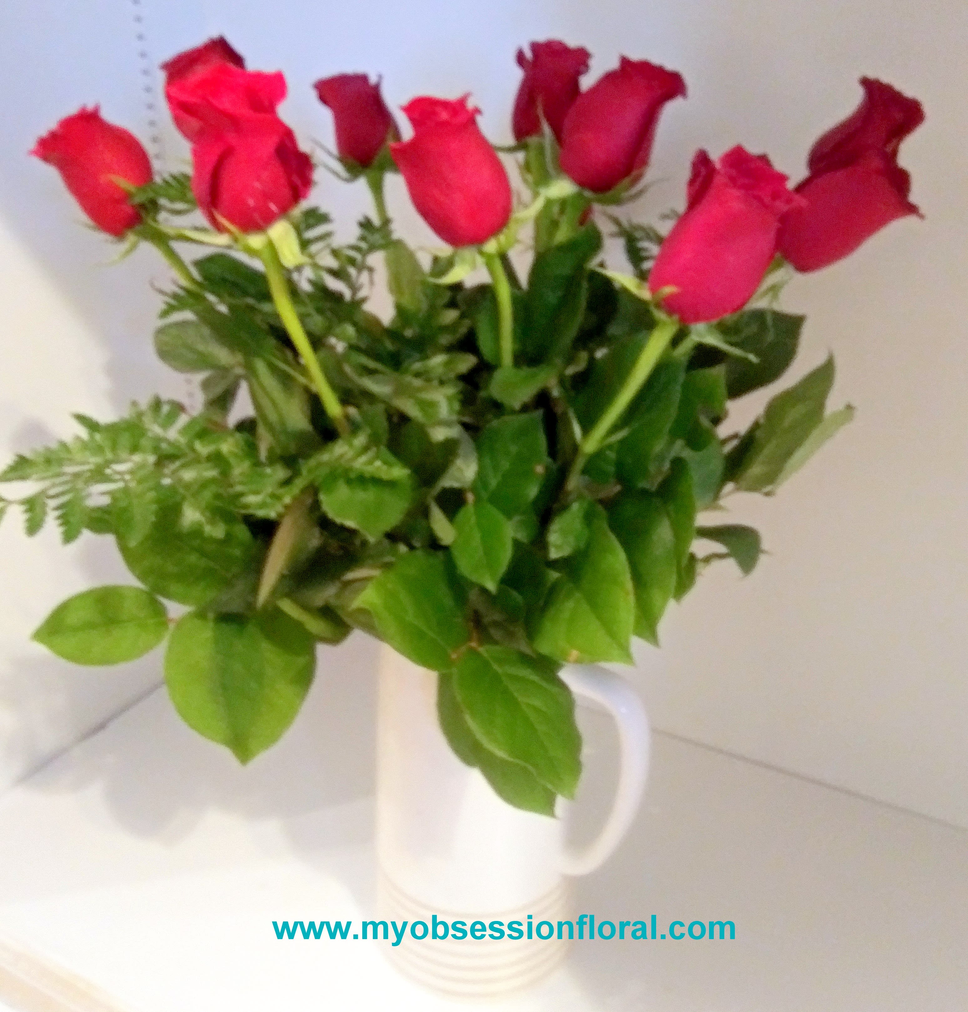 Red roses arranged in a white mug vase