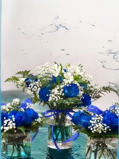 Blue and white flower arrangements in glass vases with ribbon