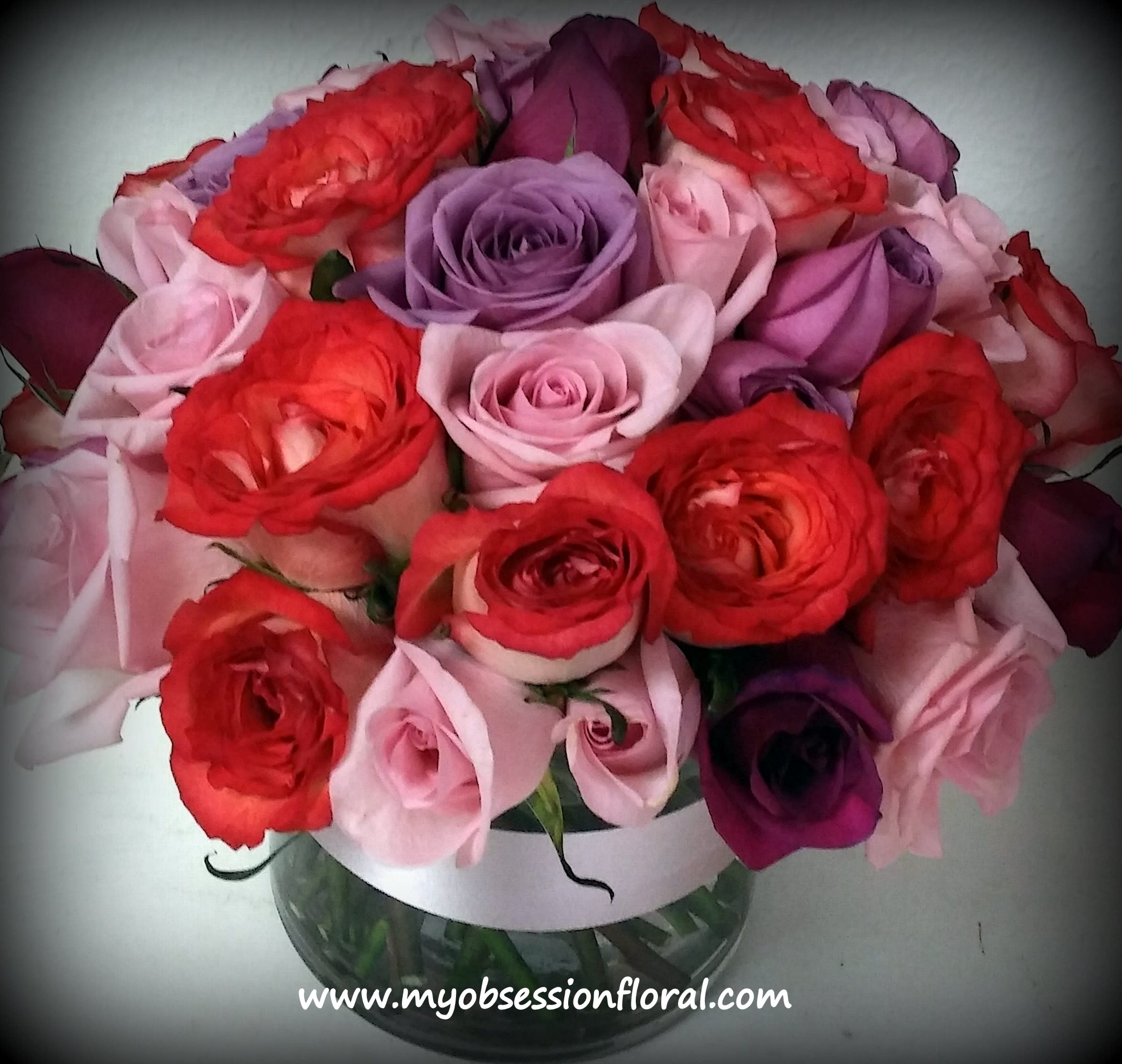 Bouquet of red, pink, and purple roses in a glass vase